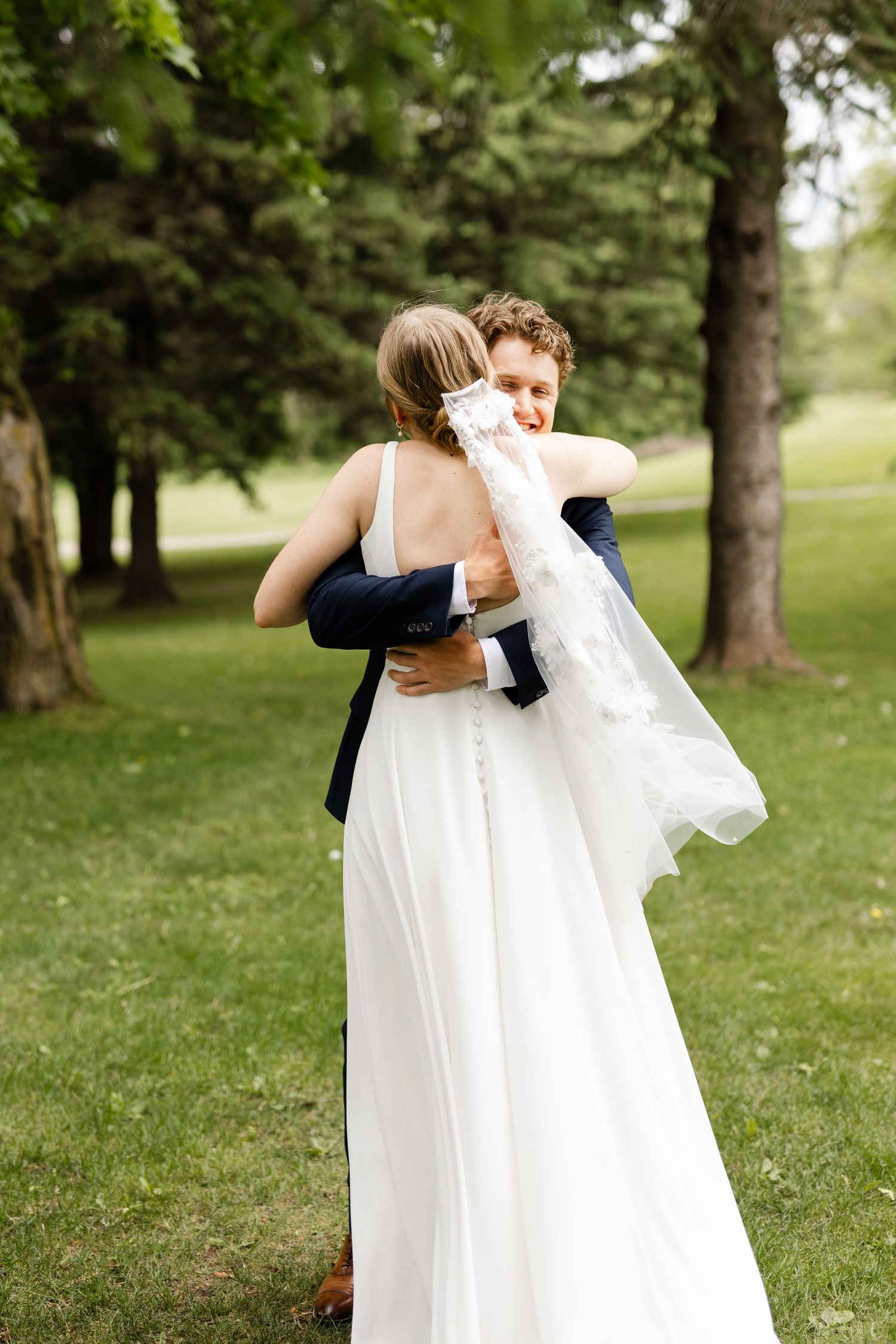 Emotional embrace between couple during outdoor wedding first look.