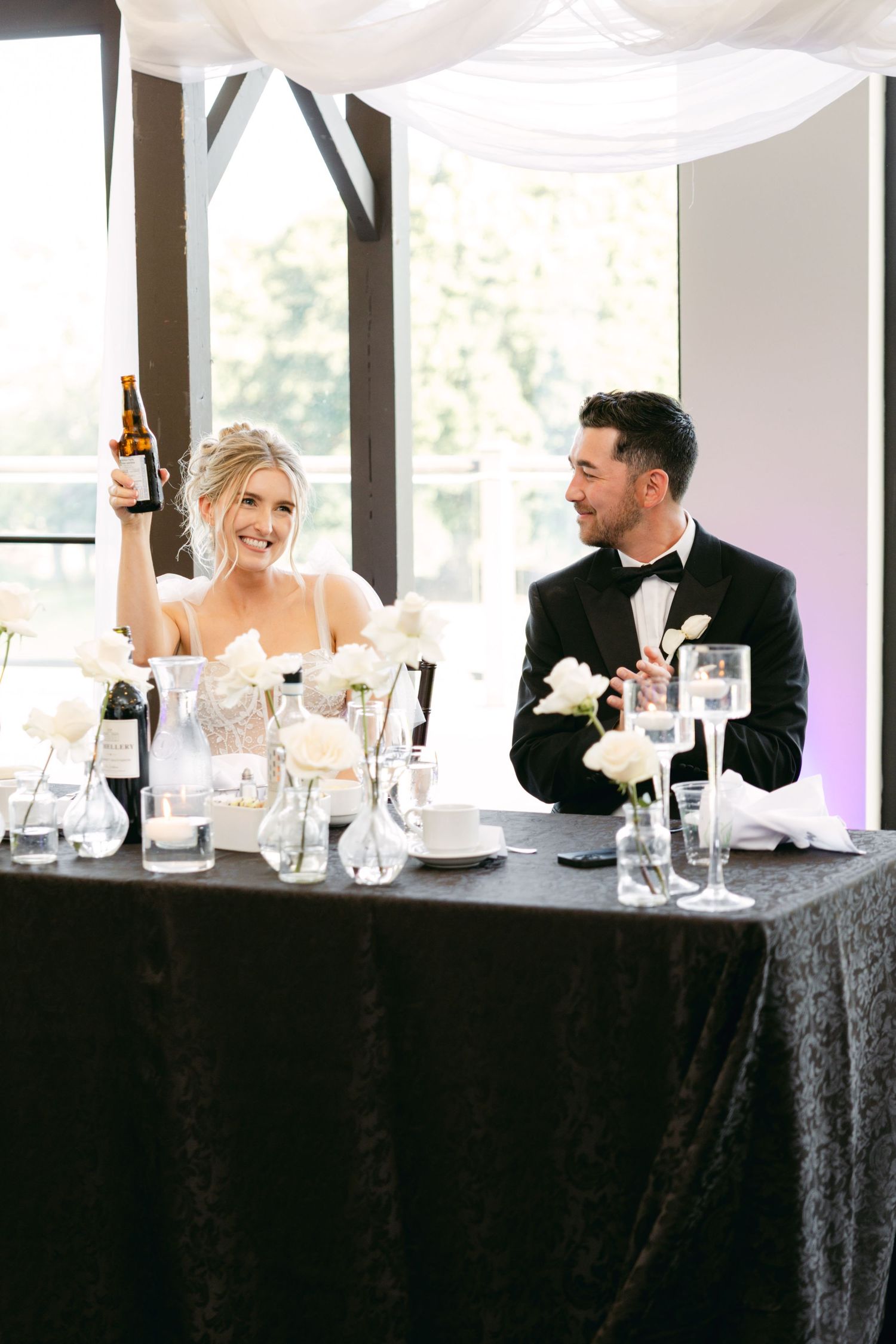 Wedding party seated at head table shares laughs during reception.