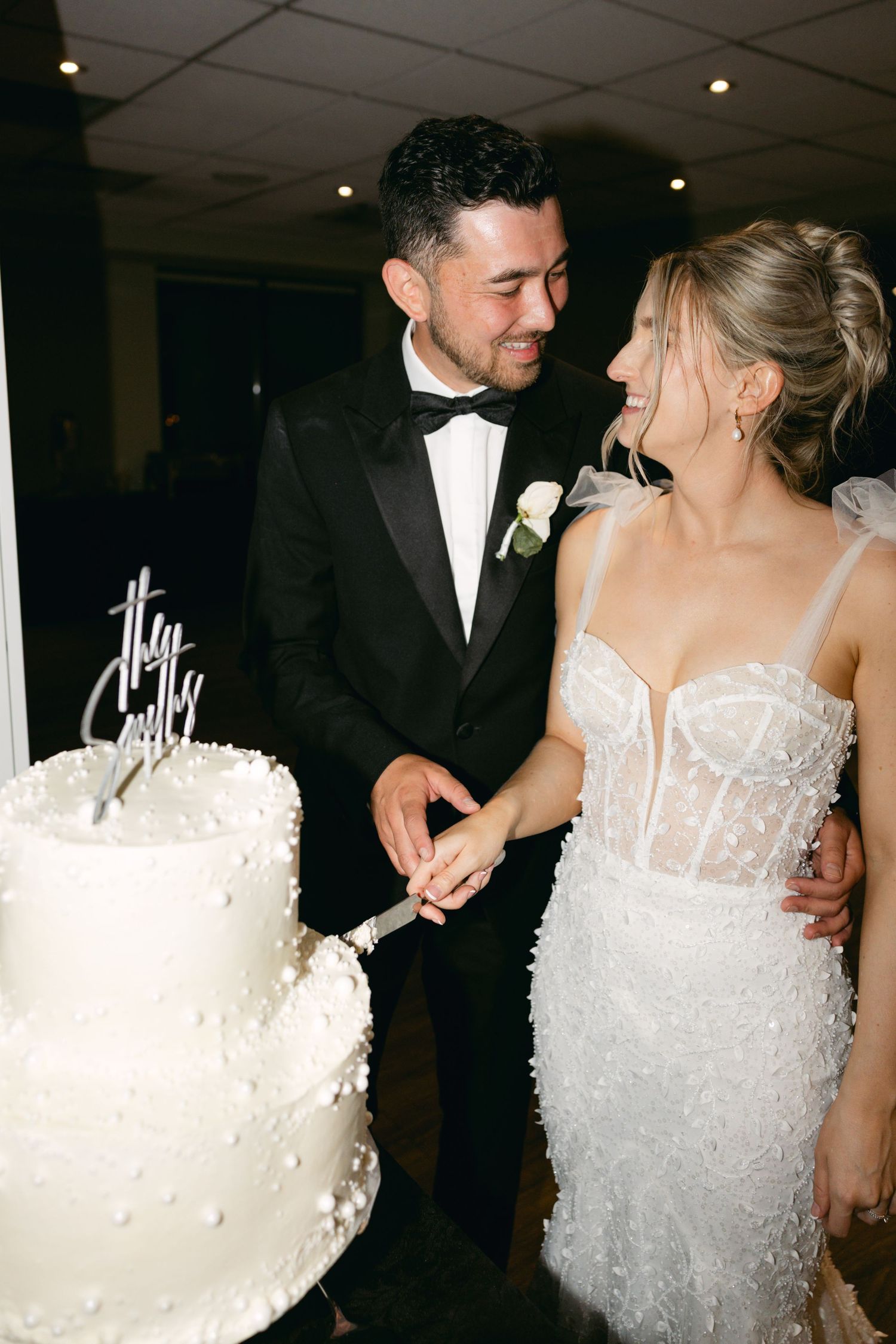 Bride and groom participate in traditional cake cutting ceremony at wedding reception.
