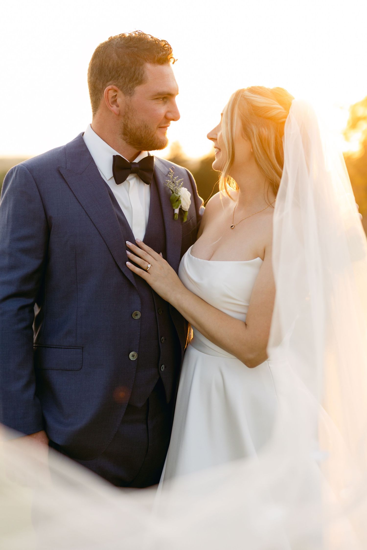 Intimate sunset portrait of newlyweds sharing a tender moment outdoors.