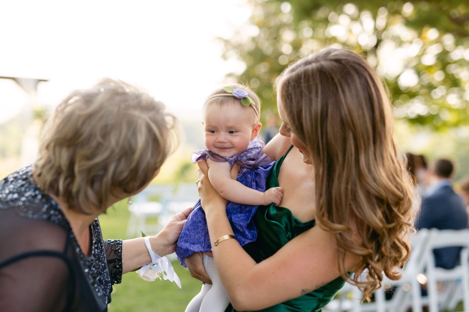 Tender moment shared with baby in blue dress at outdoor wedding reception.