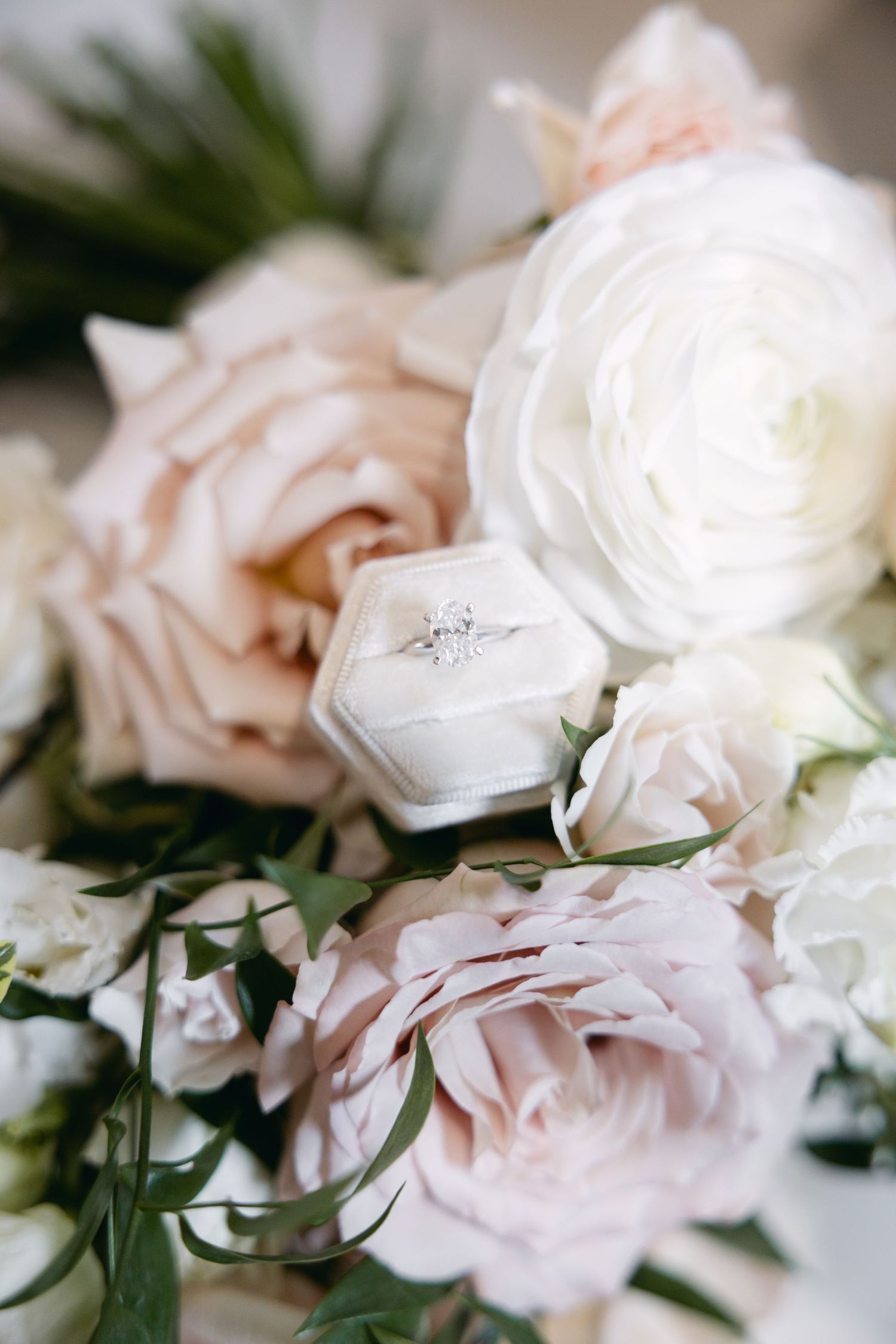 Delicate white and blush pink roses arranged with greenery in soft focus.
