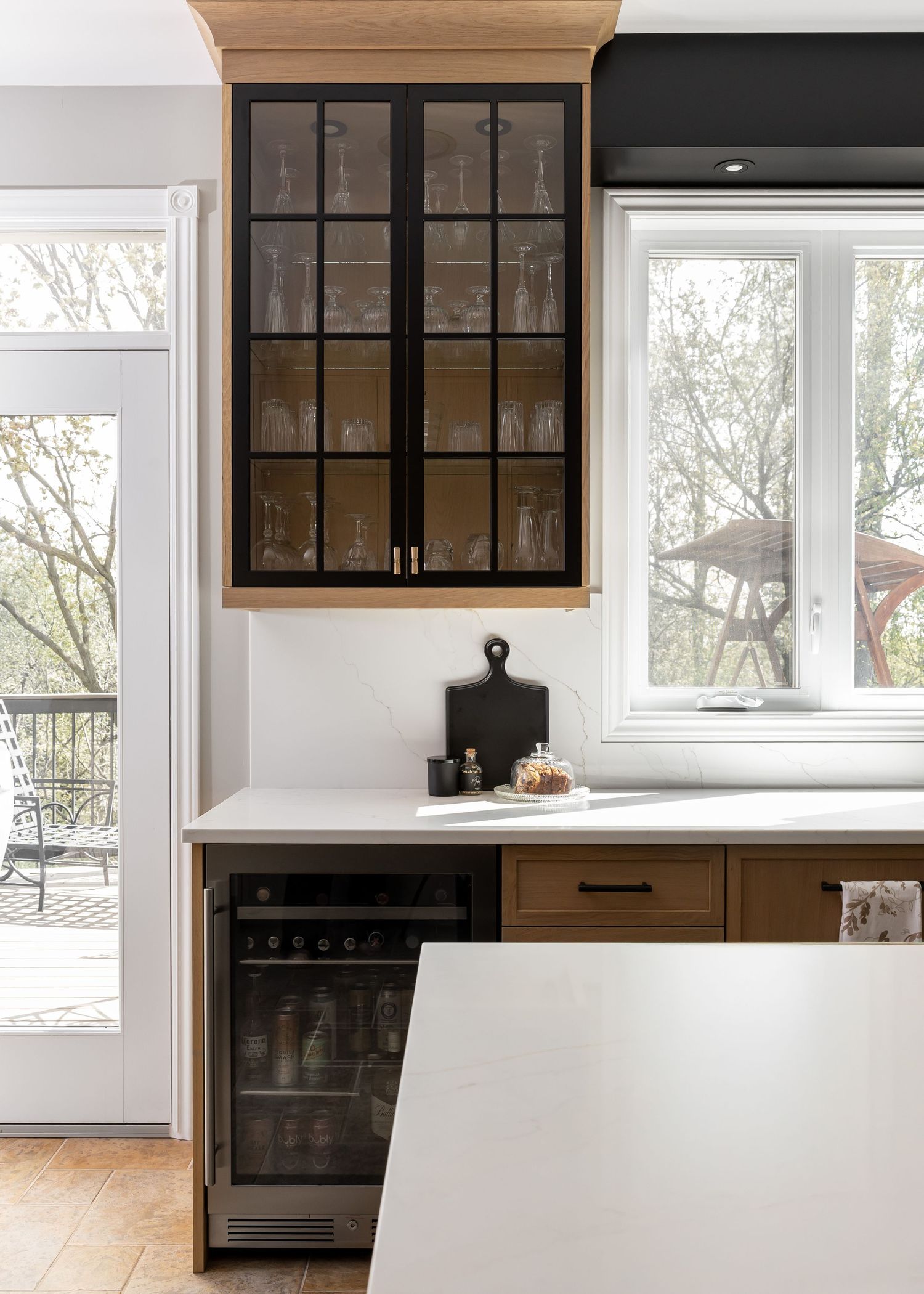 Modern kitchen featuring glass-front display cabinets and white waterfall countertop island.