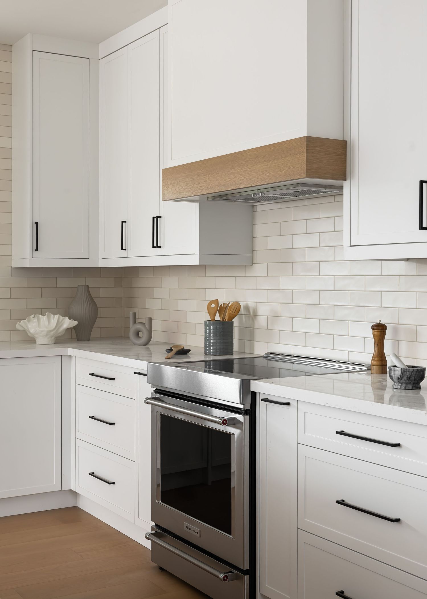 Clean white kitchen with stainless steel appliances, black hardware, and minimalist cabinetry.