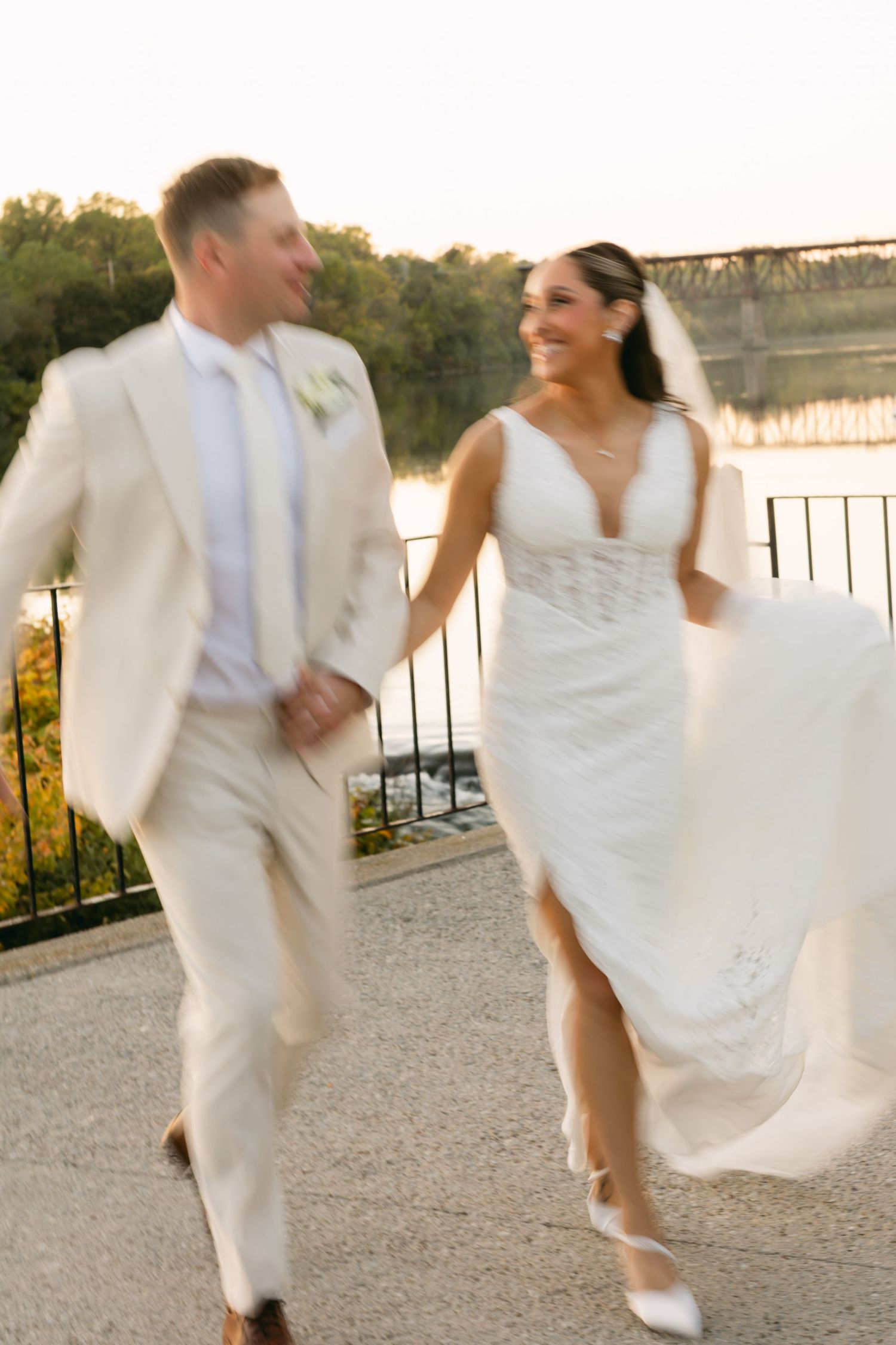 Newlyweds dancing and twirling on stone patio at sunset.