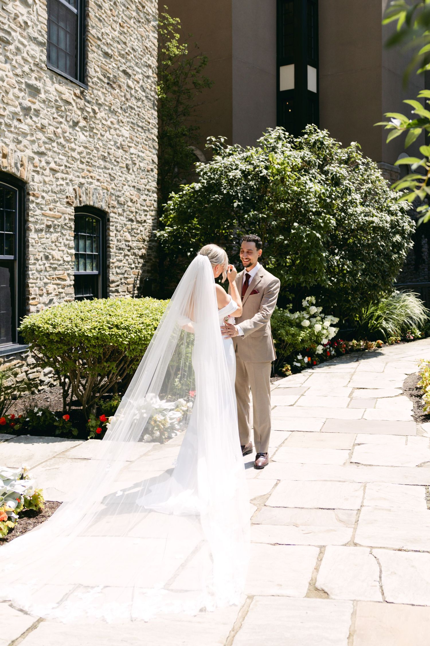Elegant wedding couple shares intimate moment on stone pathway by historic building.