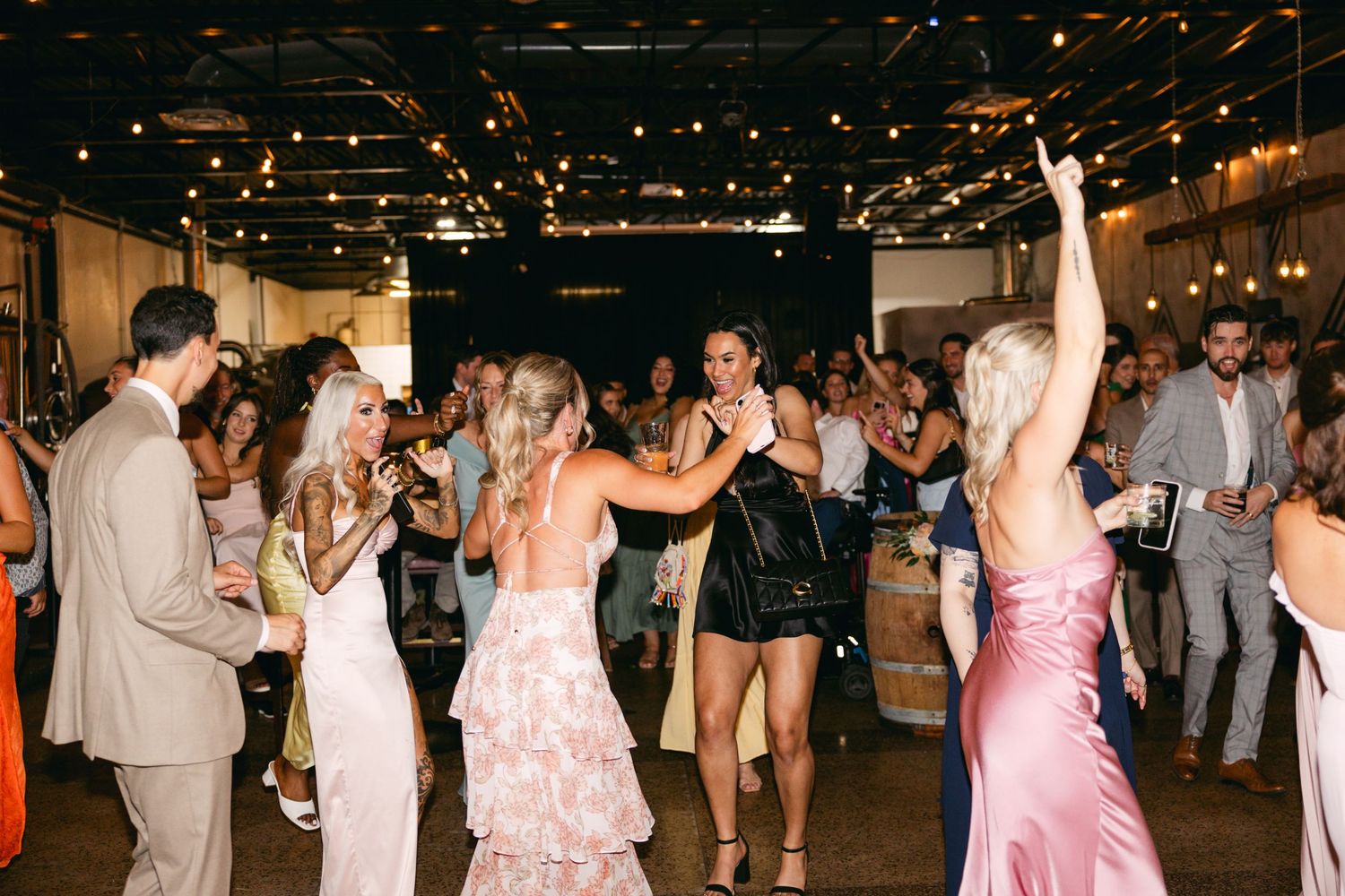 Wedding reception dance floor filled with guests celebrating under string lights.