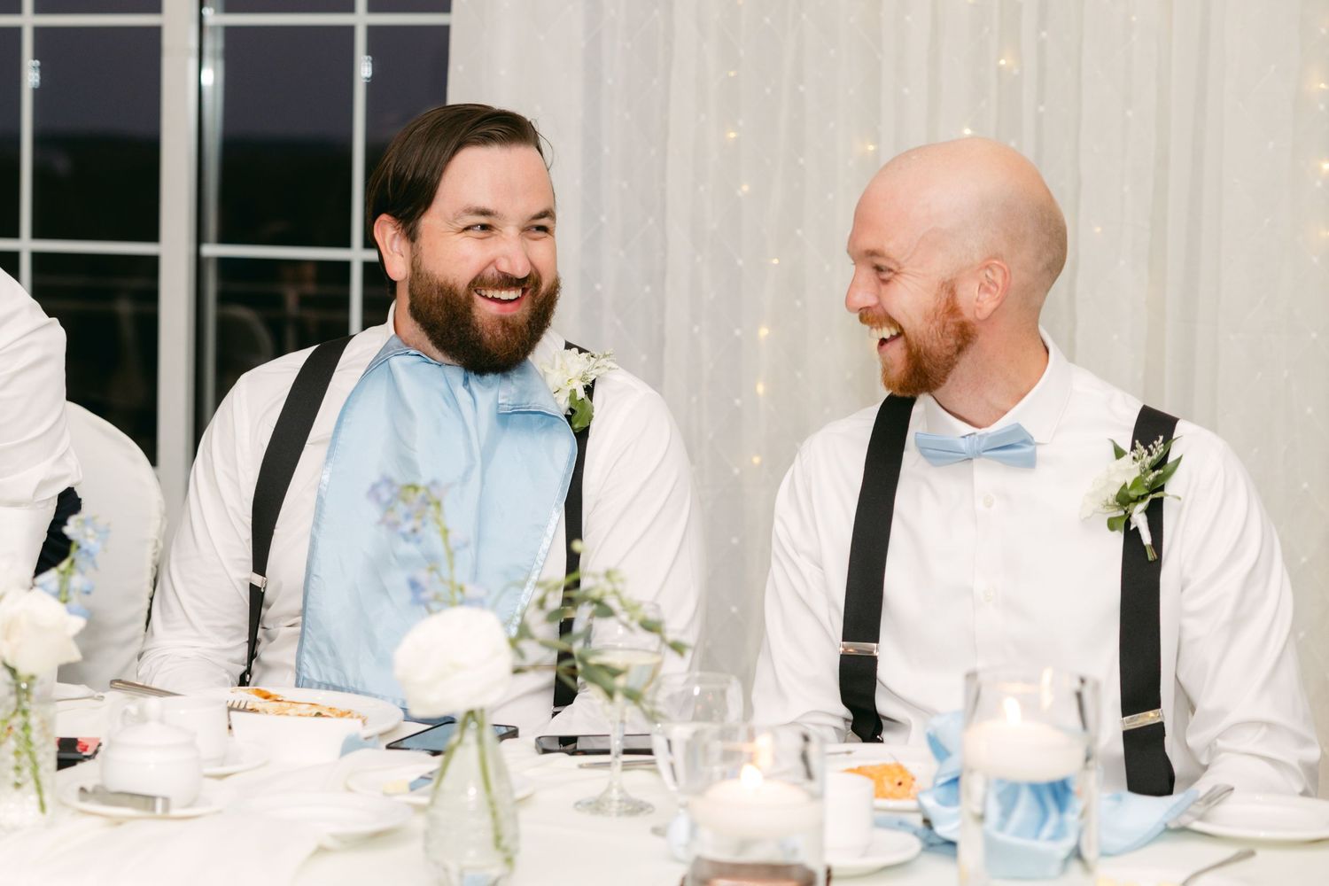 Wedding reception tables decorated with elegant white floral centerpieces and blue accents.