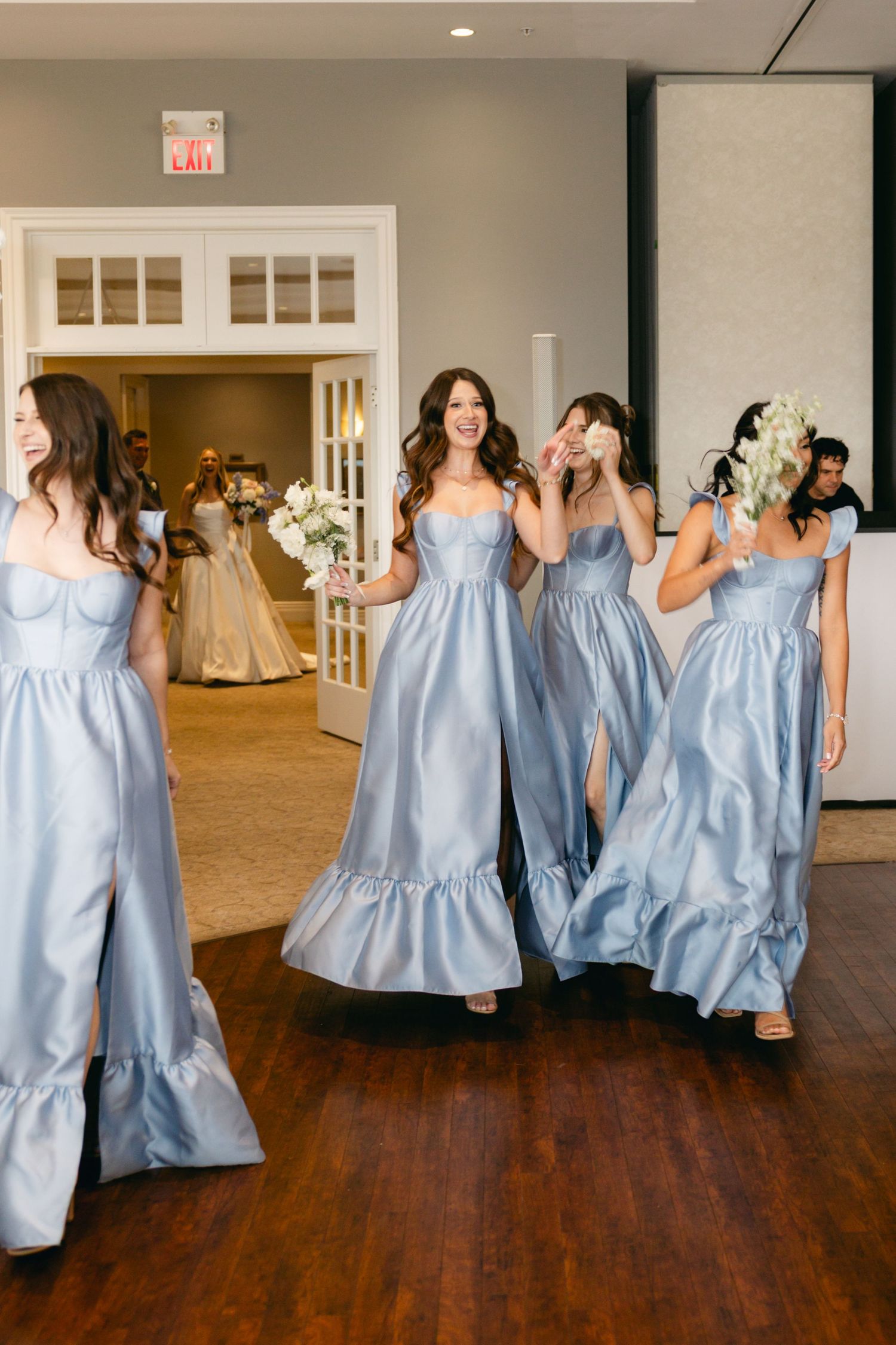 Bridesmaids in light blue dresses performing choreographed dance moves at wedding reception.