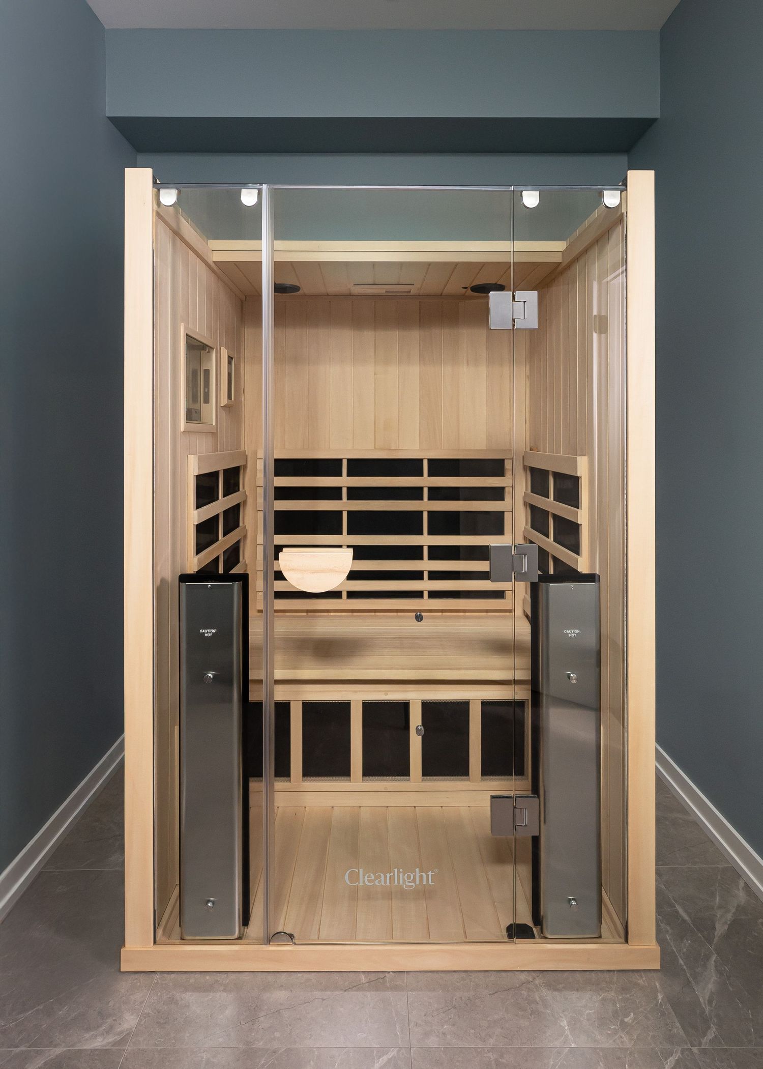 Built-in wooden sauna with glass doors and dark teal walls.