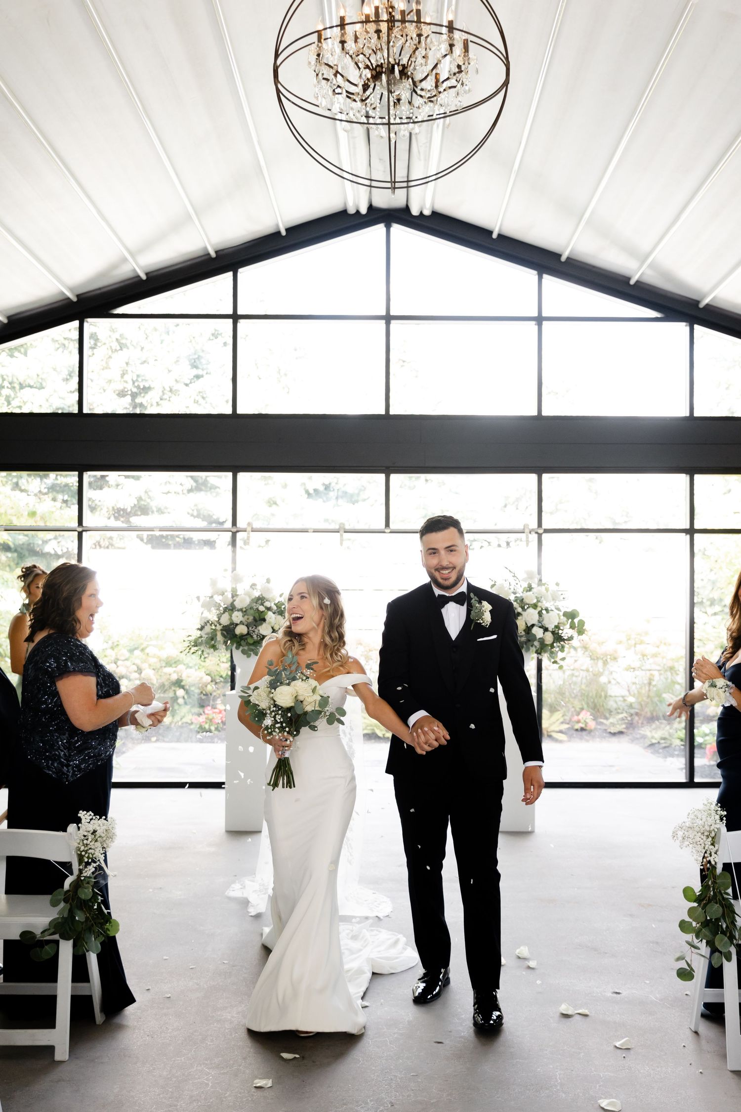 Wedding ceremony setup in modern venue with chandeliers and large windows.