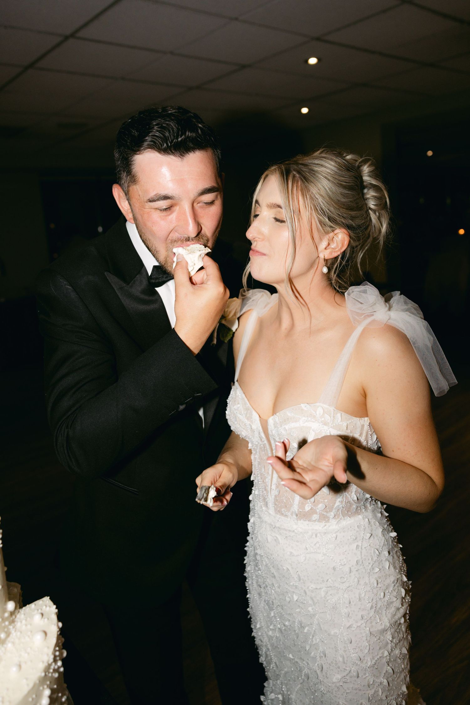 Couple shares intimate moment during wedding cake feeding tradition.