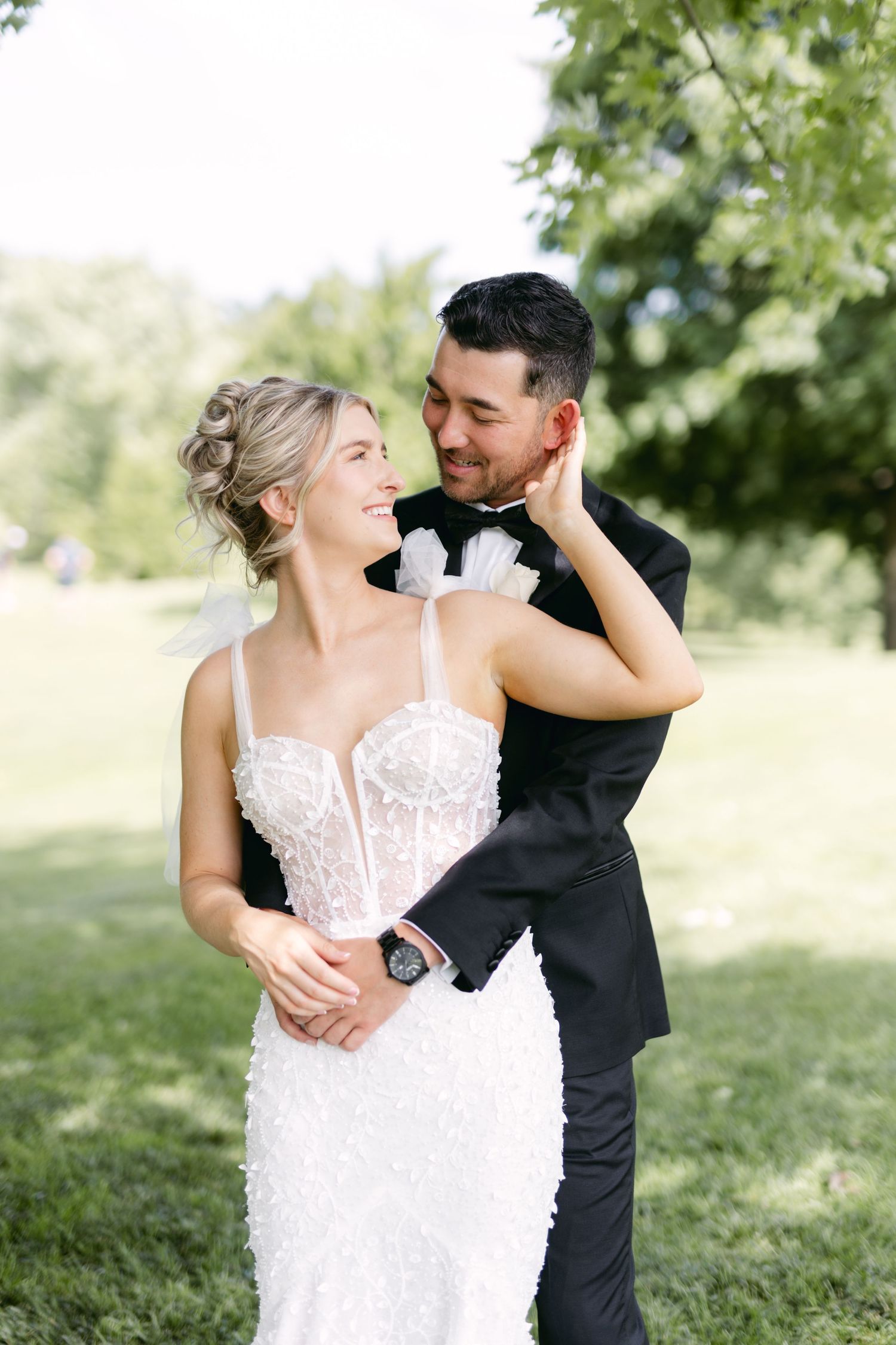A joyful wedding moment captured outdoors with the couple sharing a tender embrace.