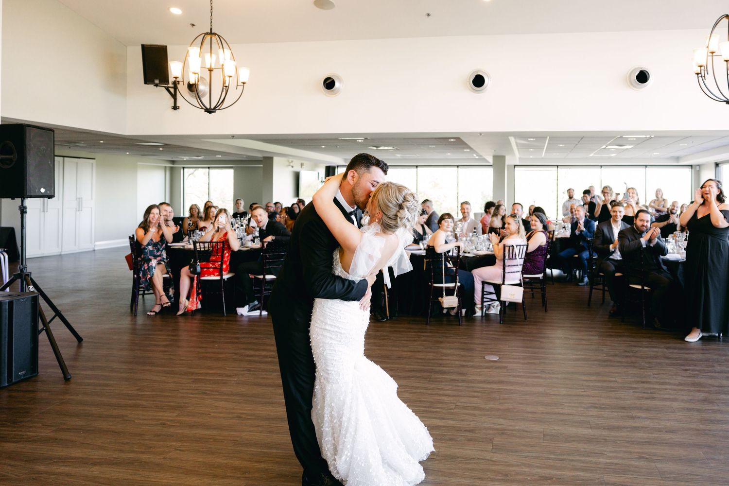 Wedding reception venue with elegant chandeliers and large windows overlooking a scenic view.