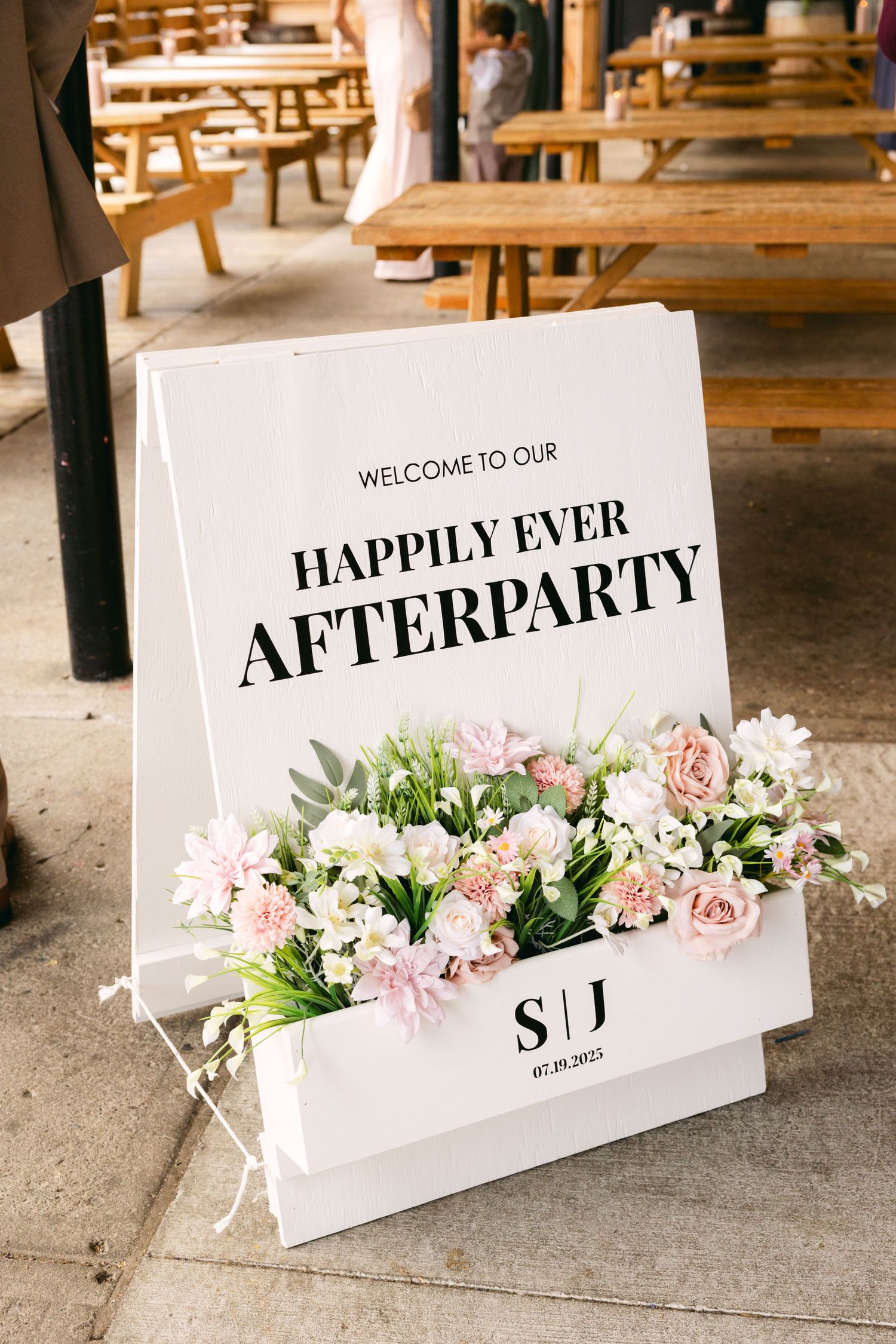 Wedding reception signs with floral decorations display 'Happily Ever' and 'Afterparty' text.