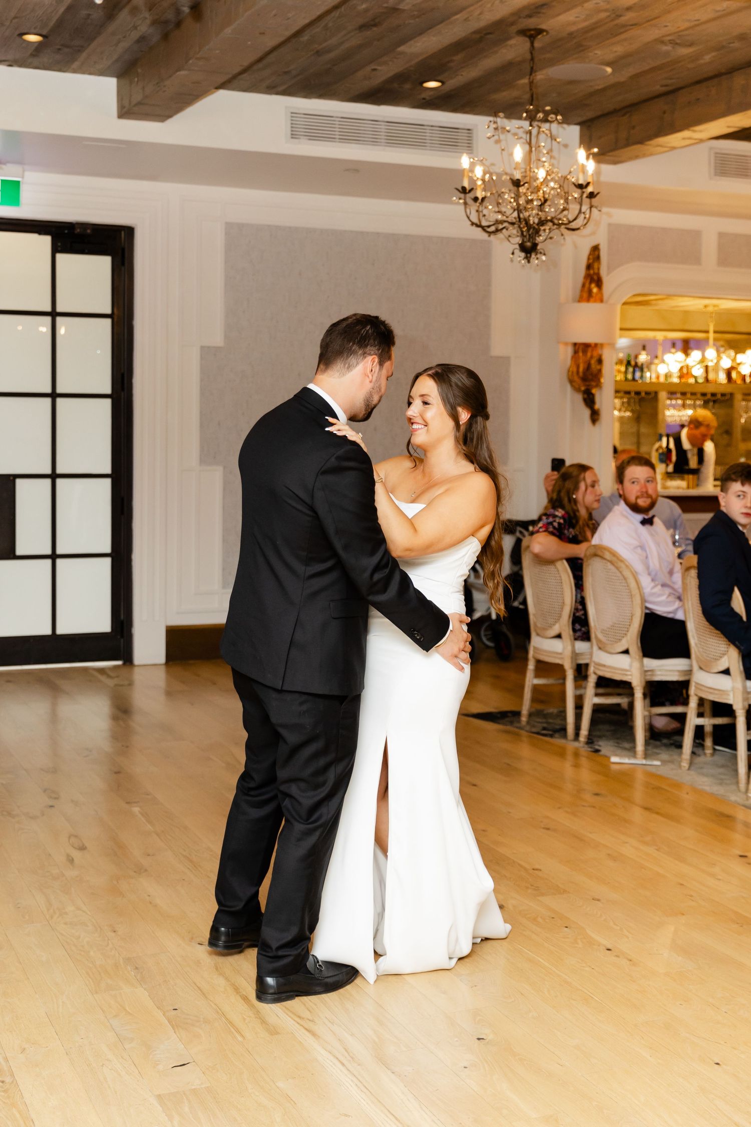 Bride and groom share their first dance in a warmly lit elegant wedding reception venue.