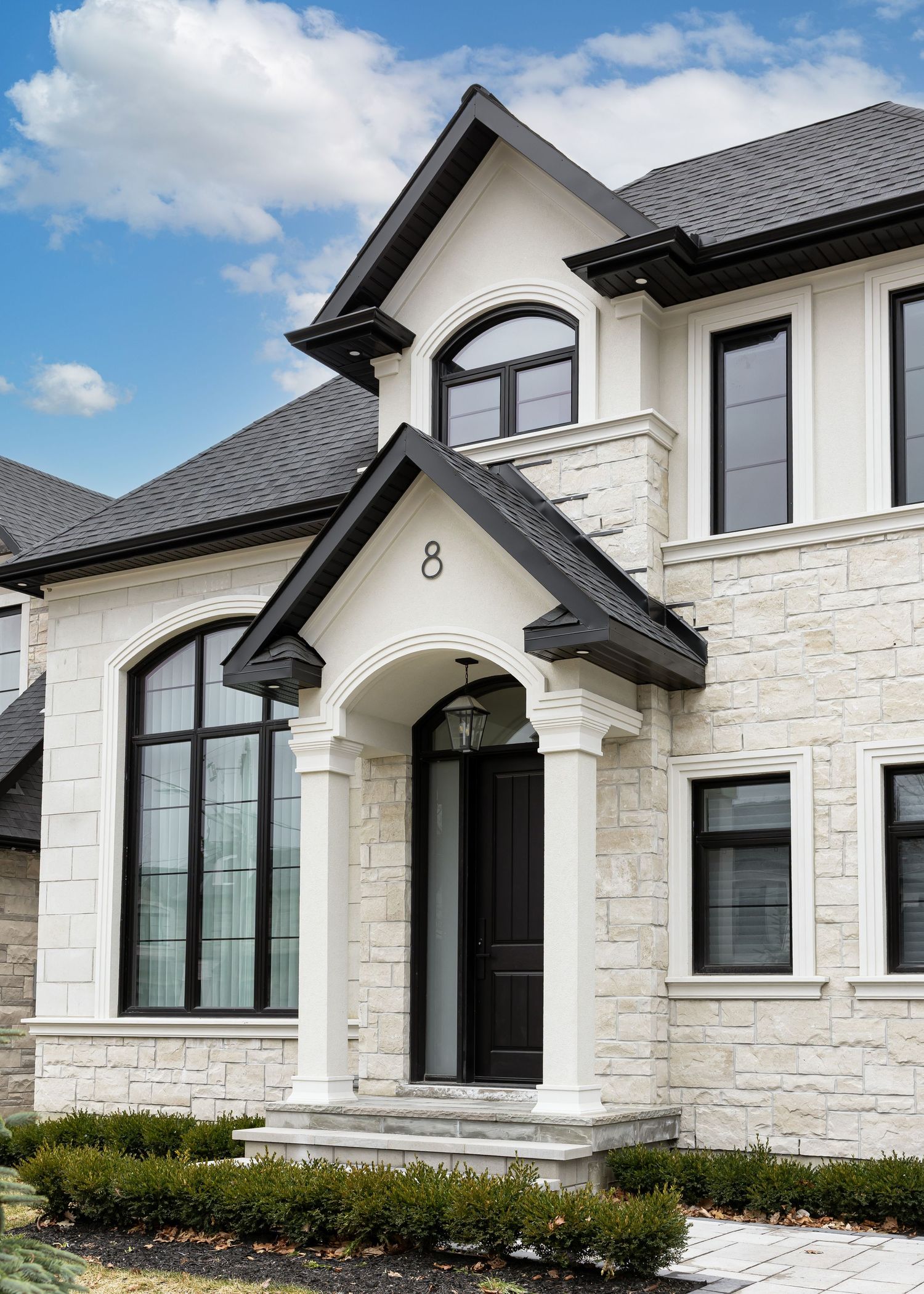 Luxury stone facade home with arched entryway and black trim details.