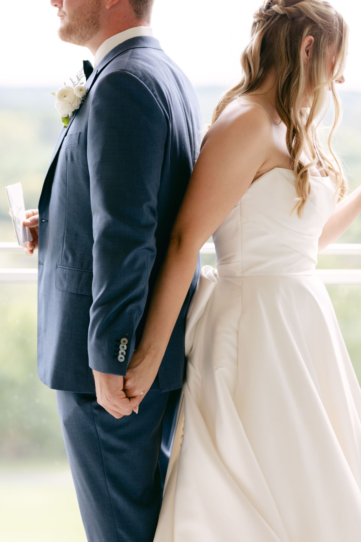 Intimate moment captured of couple in wedding attire standing back to back.