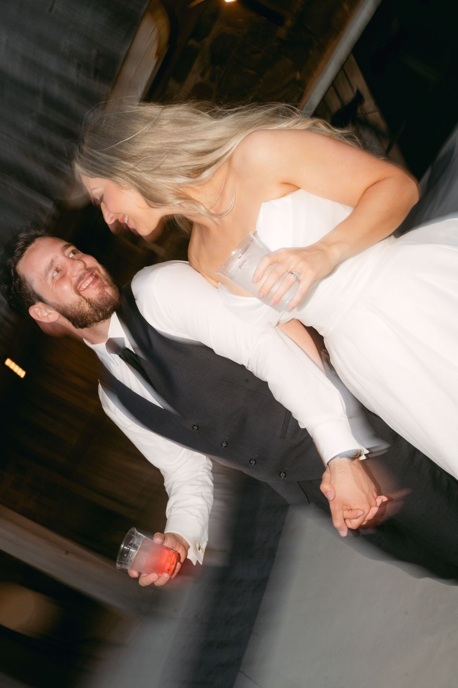 Wedding couple dances dramatically in a dark reception venue.