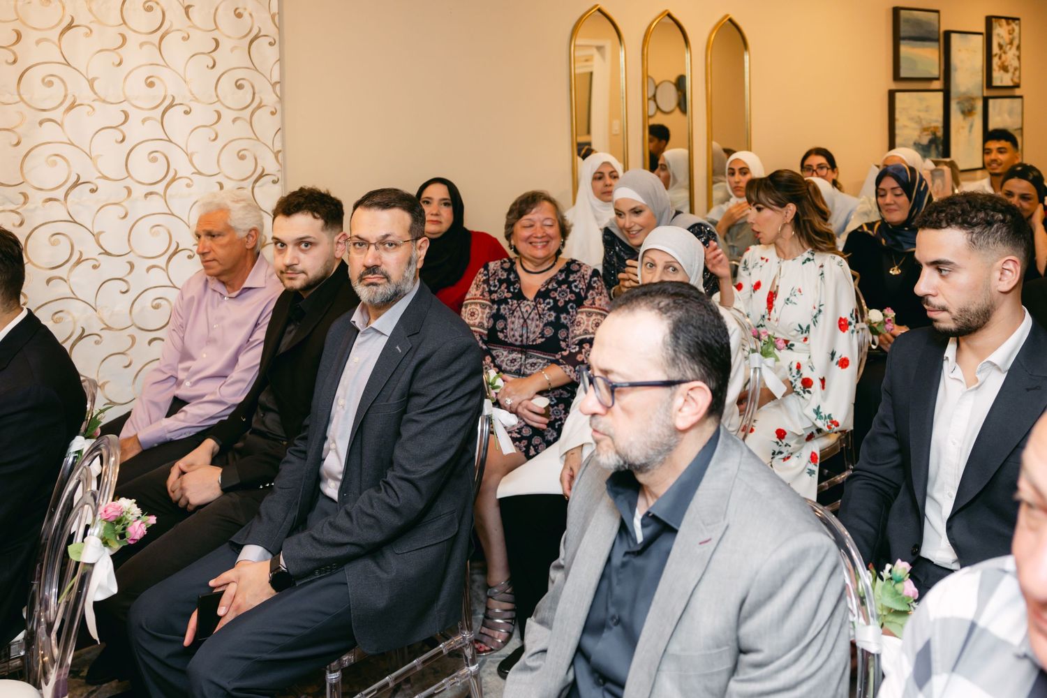 Guests seated in rows at an indoor event with decorative wall patterns.
