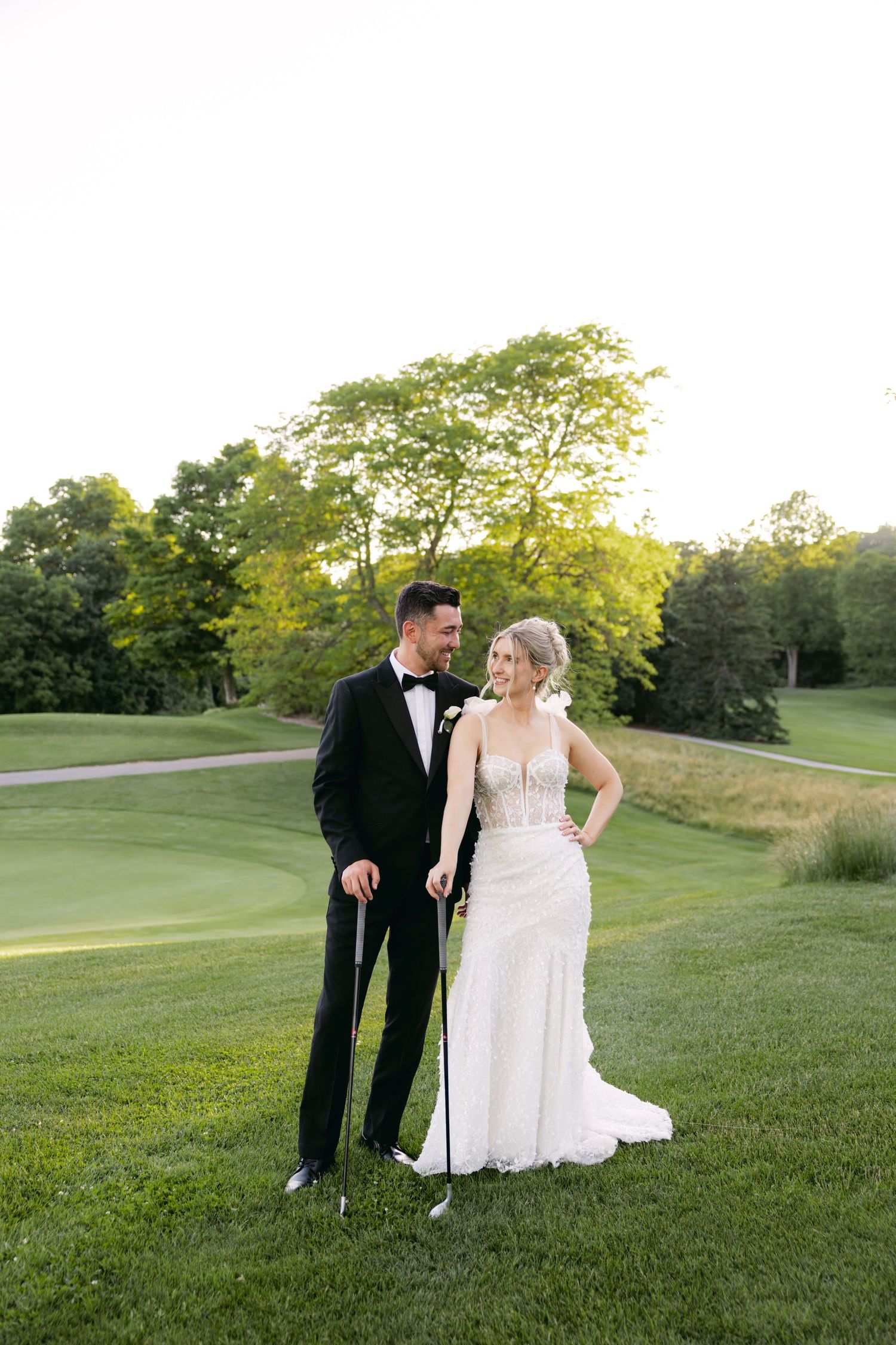 Newlyweds share joyful moments while walking on a lush green golf course.