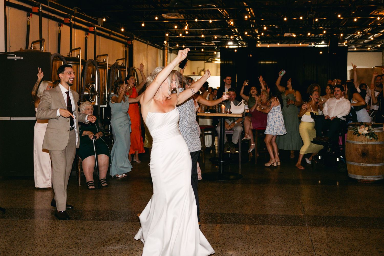 Wedding reception dance floor filled with celebrating guests under string lights.