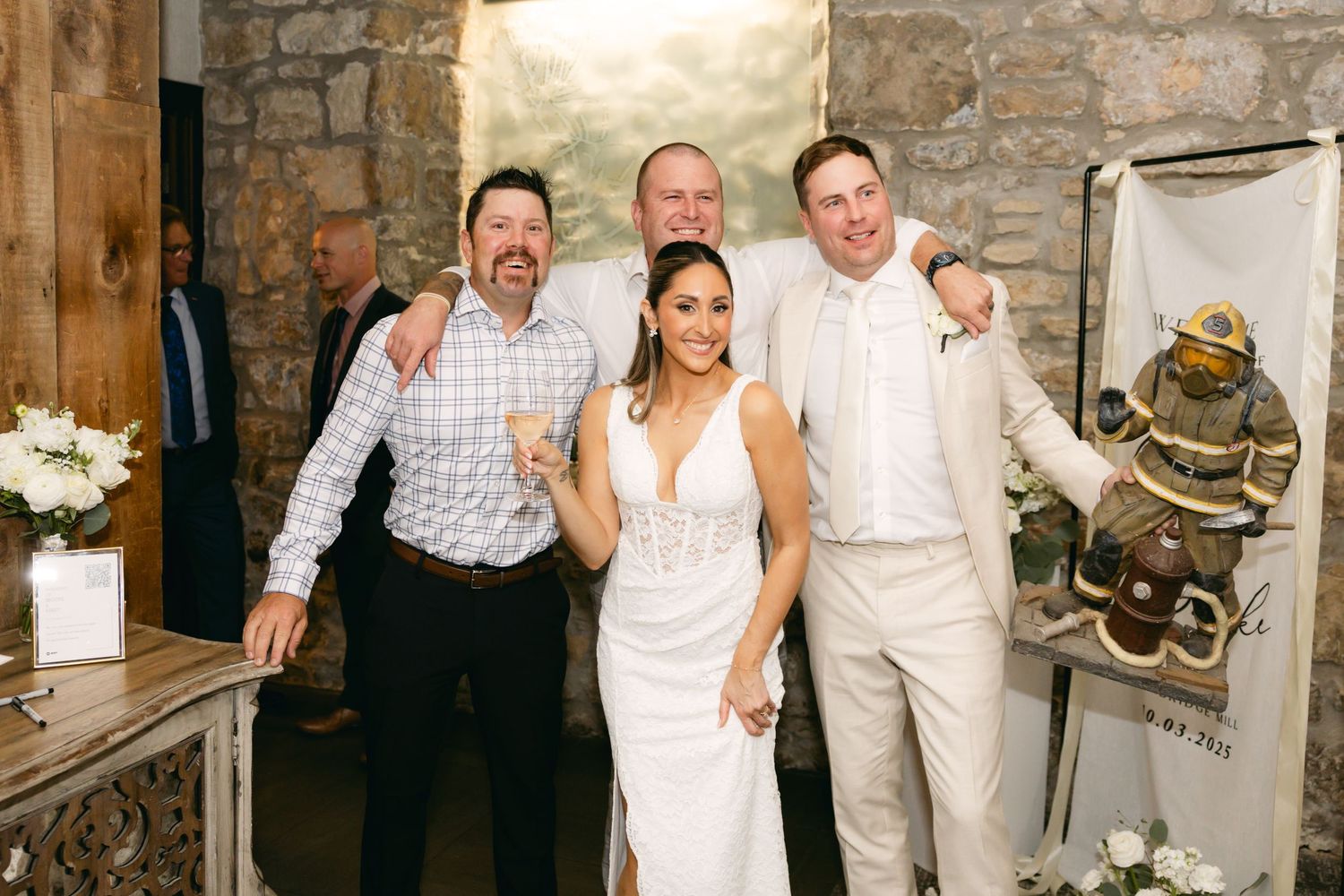Wedding party posing together against rustic stone wall background.