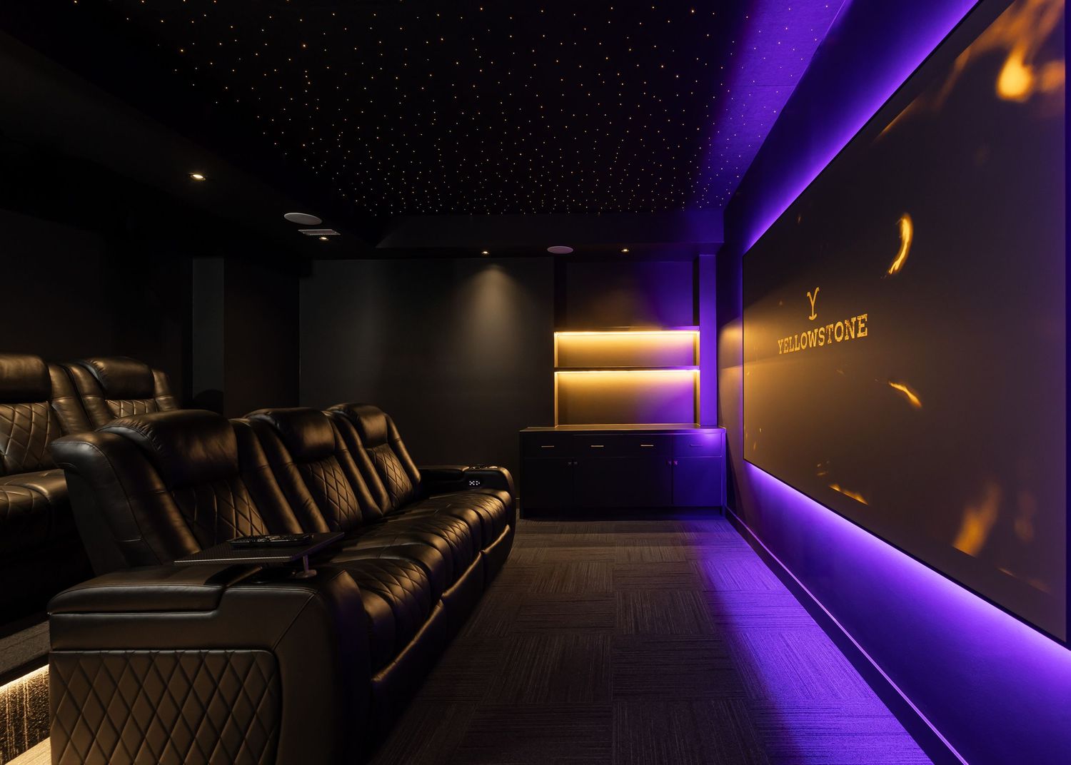 Home theater room with purple LED accent lighting and comfortable reclining seats.
