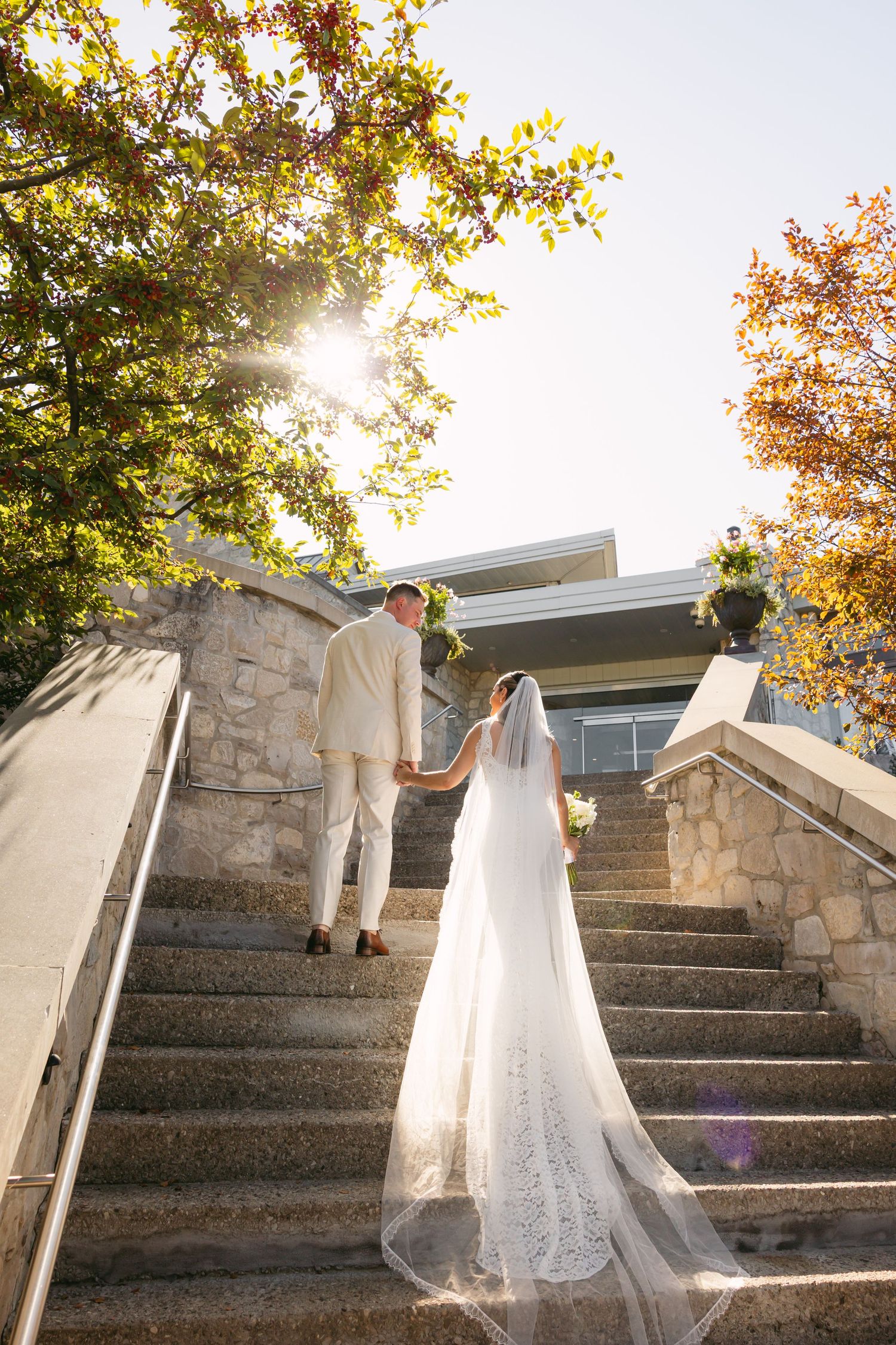 Wedding couple ascends stone steps during golden hour photography session.