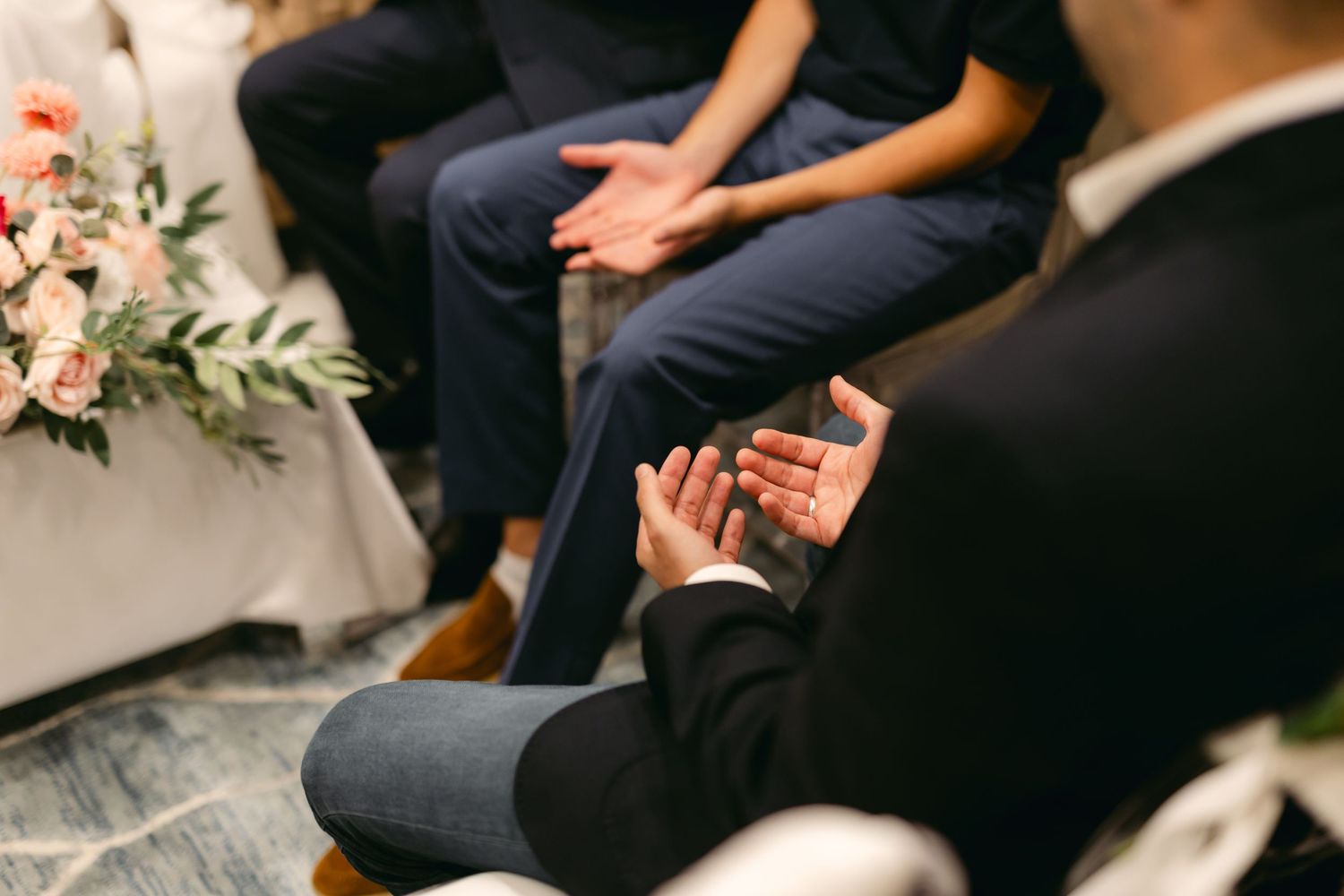 Hands holding documents during an intimate indoor ceremony with floral decorations and white drapes.