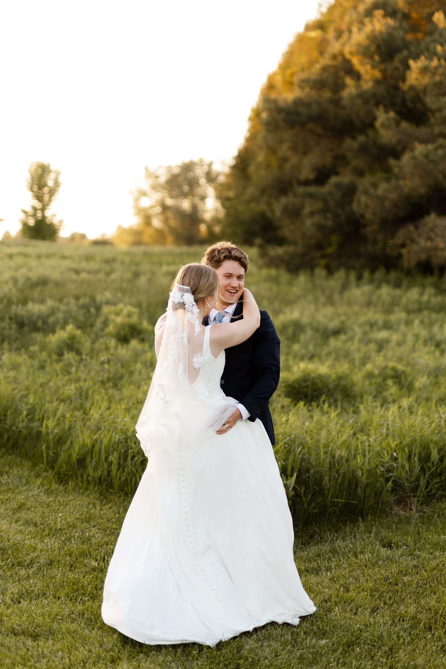 Wedding couple shares a romantic dance in a sunlit meadow.