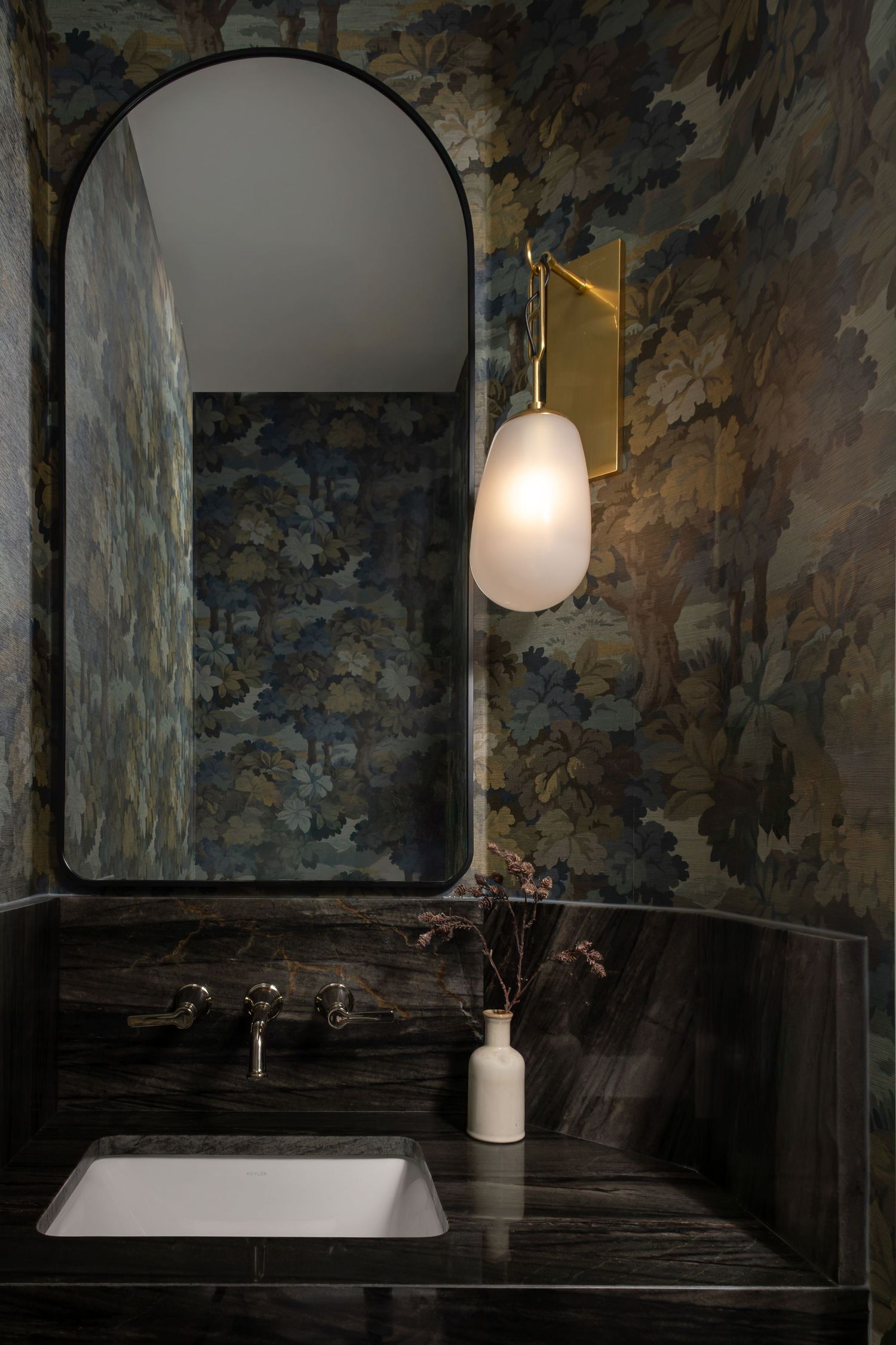Moody bathroom with dramatic wallpaper, arched doorway, and freestanding tub.