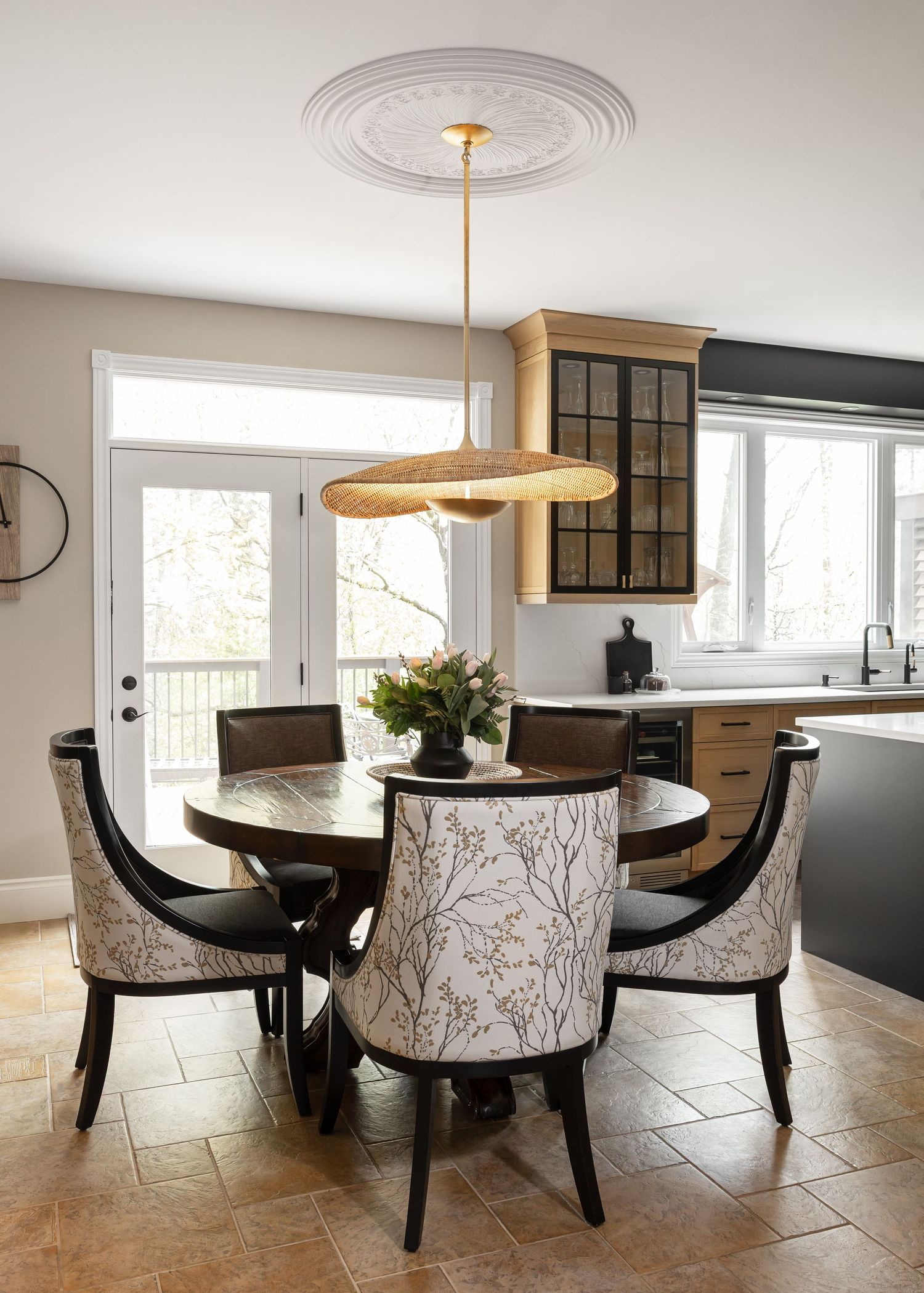Elegant dining area with round wooden table, patterned chairs, and modern disc-shaped pendant light.