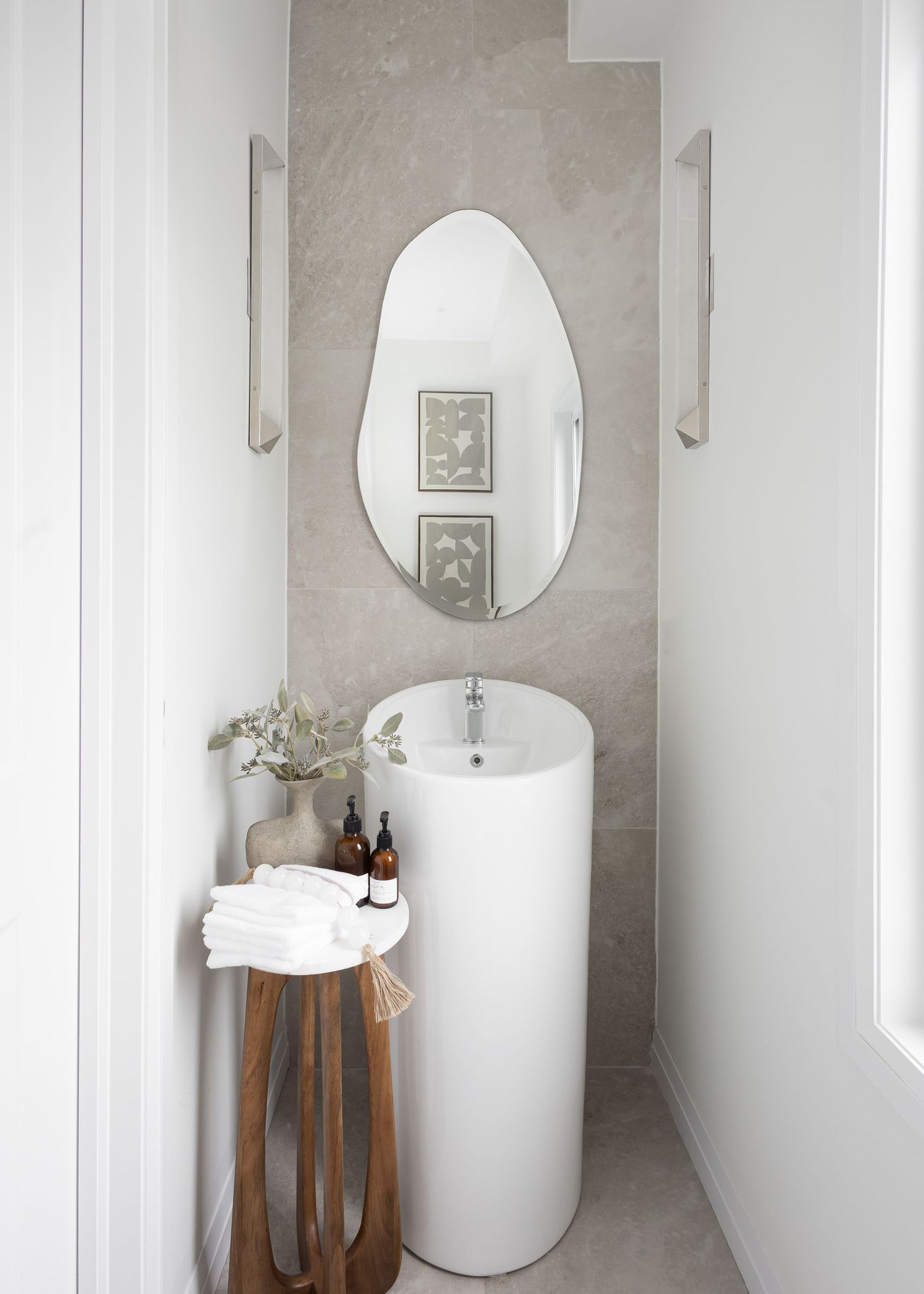 Modern bathroom interior with round mirror, wooden stand and white towels in minimalist design.