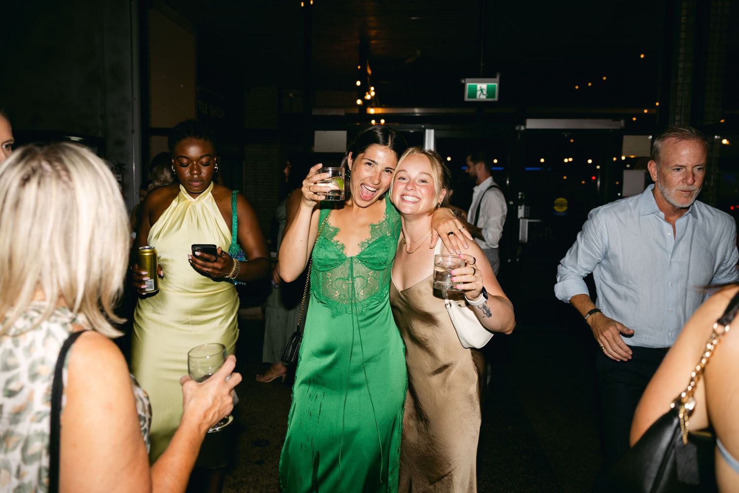 Wedding reception dance floor with guests in colorful attire under dark lighting.