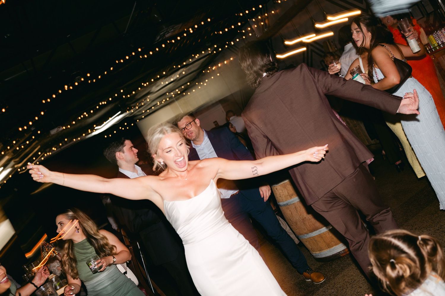 Couples dancing at wedding reception under dimly lit string lights.
