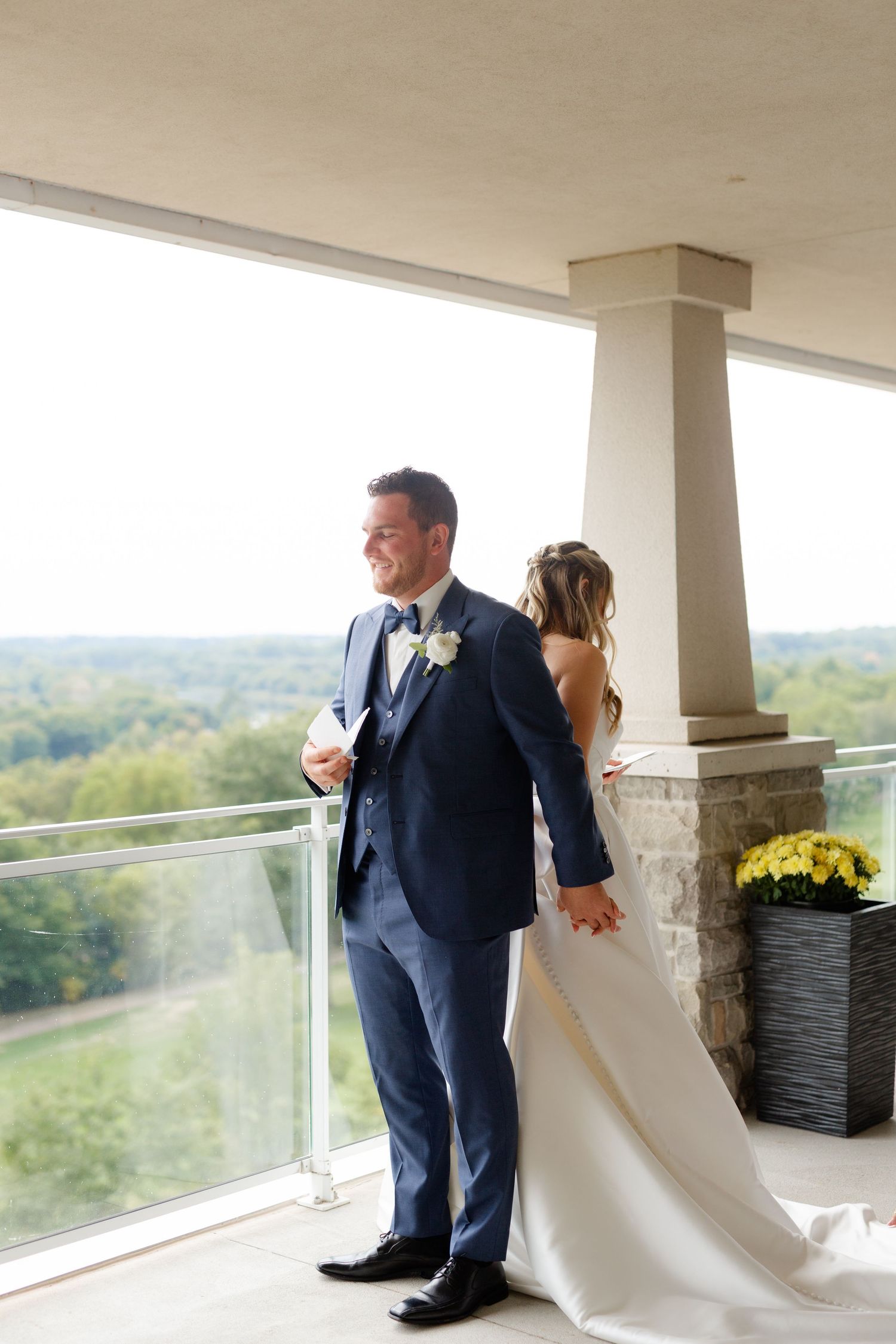 Couple shares private first look moment on balcony overlooking scenic landscape.