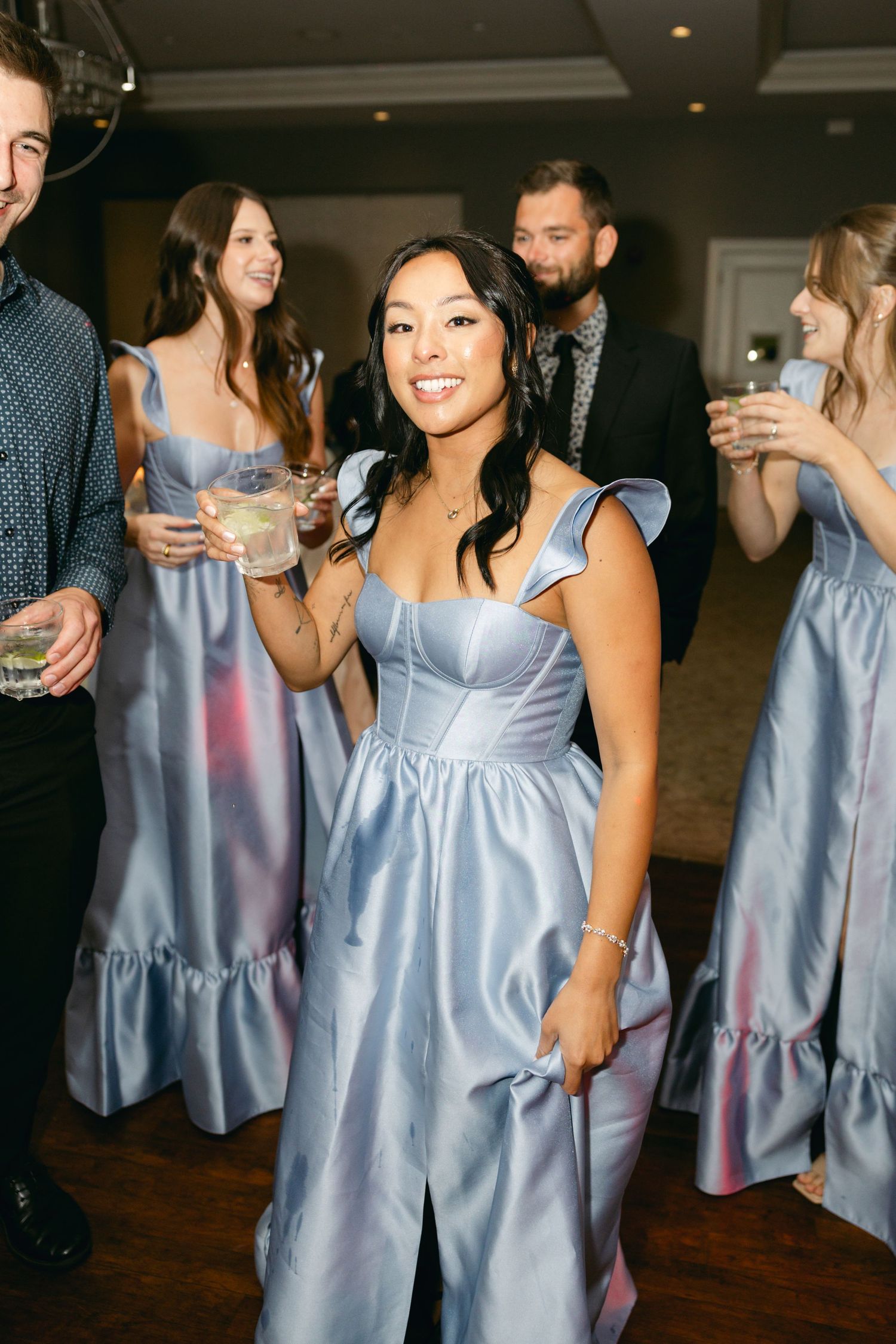 Bridesmaid in light blue satin dress enjoying reception festivities.