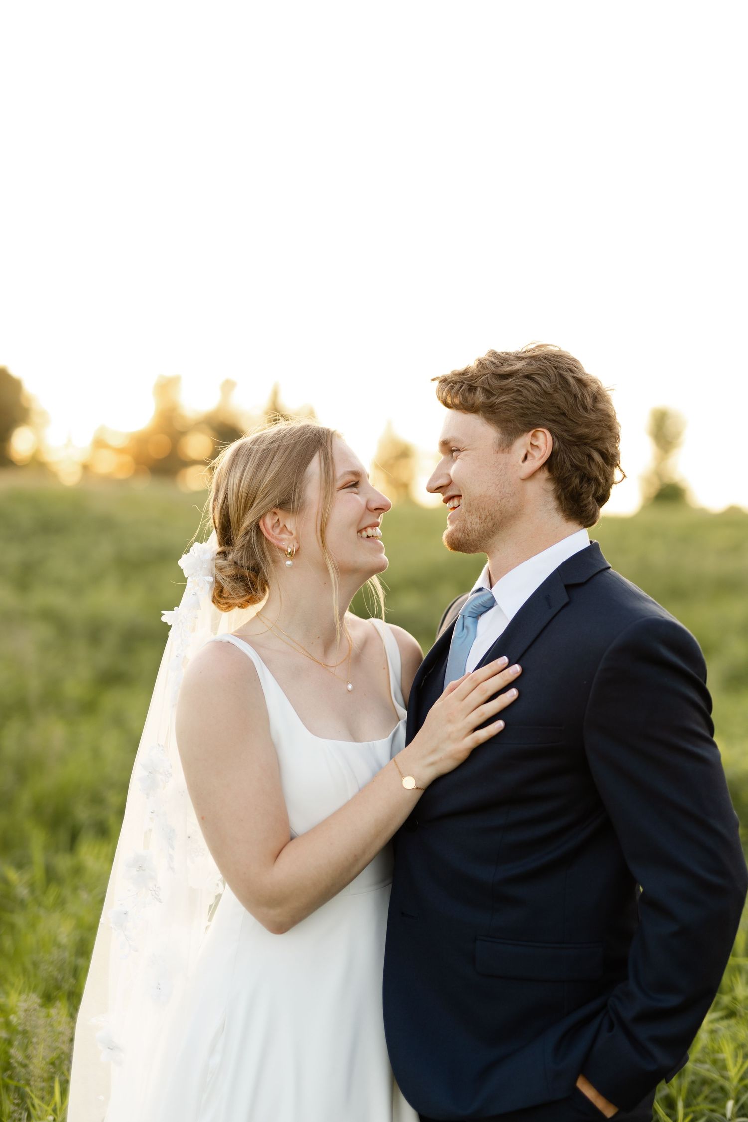Joyful wedding couple laughs together during their sunset portrait session.
