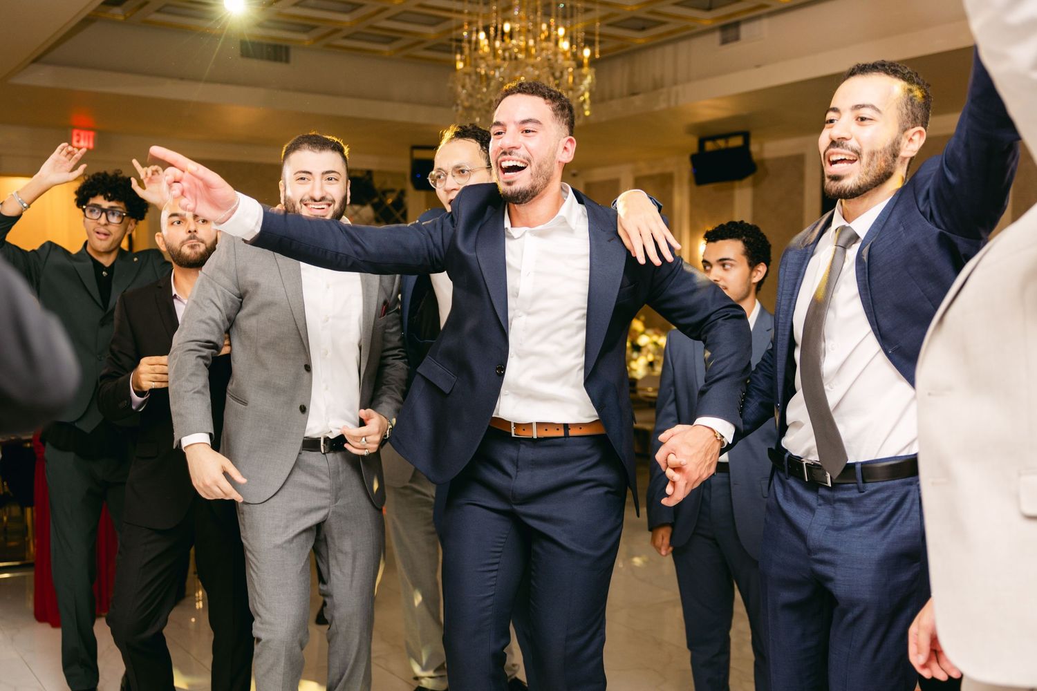 Groomsmen celebrate enthusiastically on the dance floor at a wedding reception.