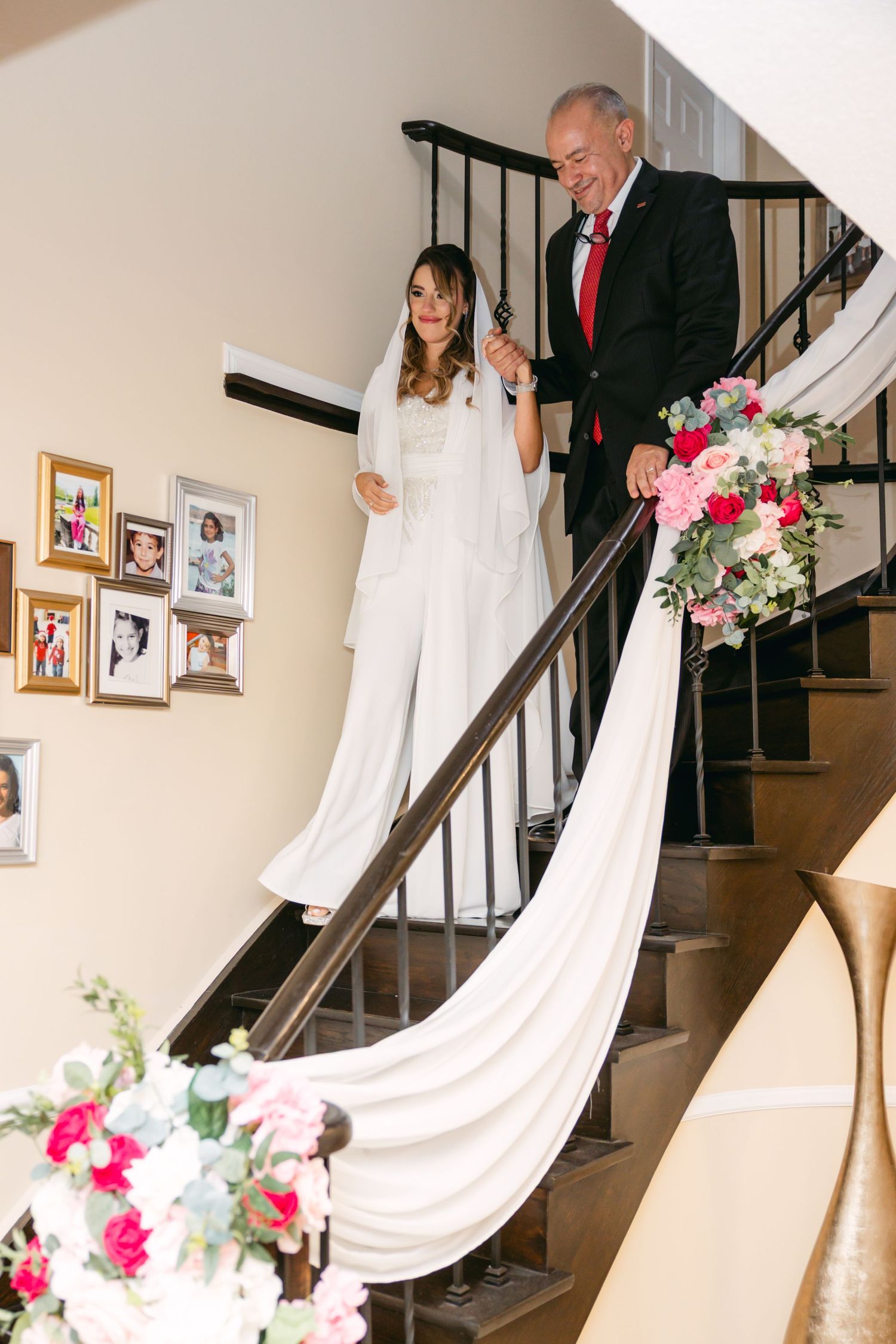 A wedding scene on a staircase with pink and white floral arrangements decorating the railing.