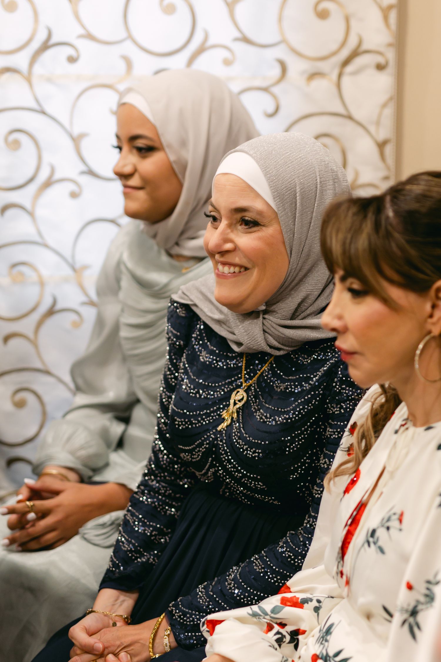 Women in elegant attire sharing a joyful moment during a formal gathering.