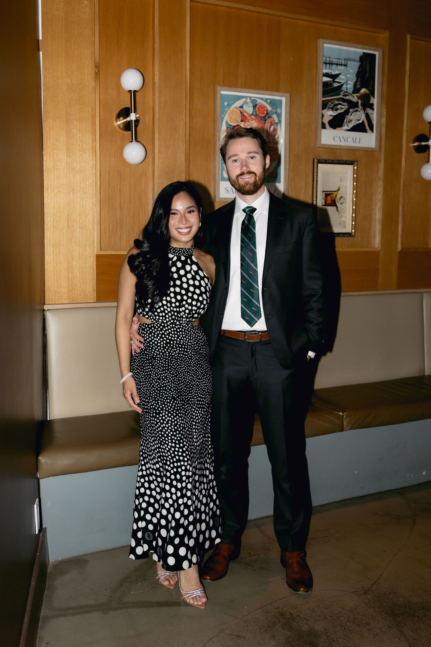 Couple posing together at a wedding reception, woman in polka dot dress and man in suit.