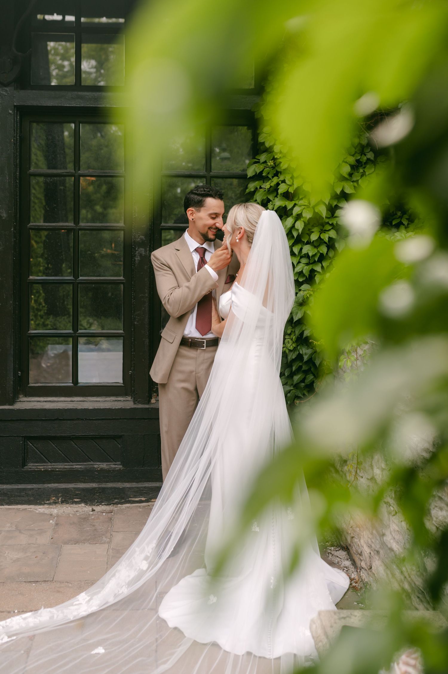 Romantic garden wedding photos with flowing veil and lush greenery backdrop.