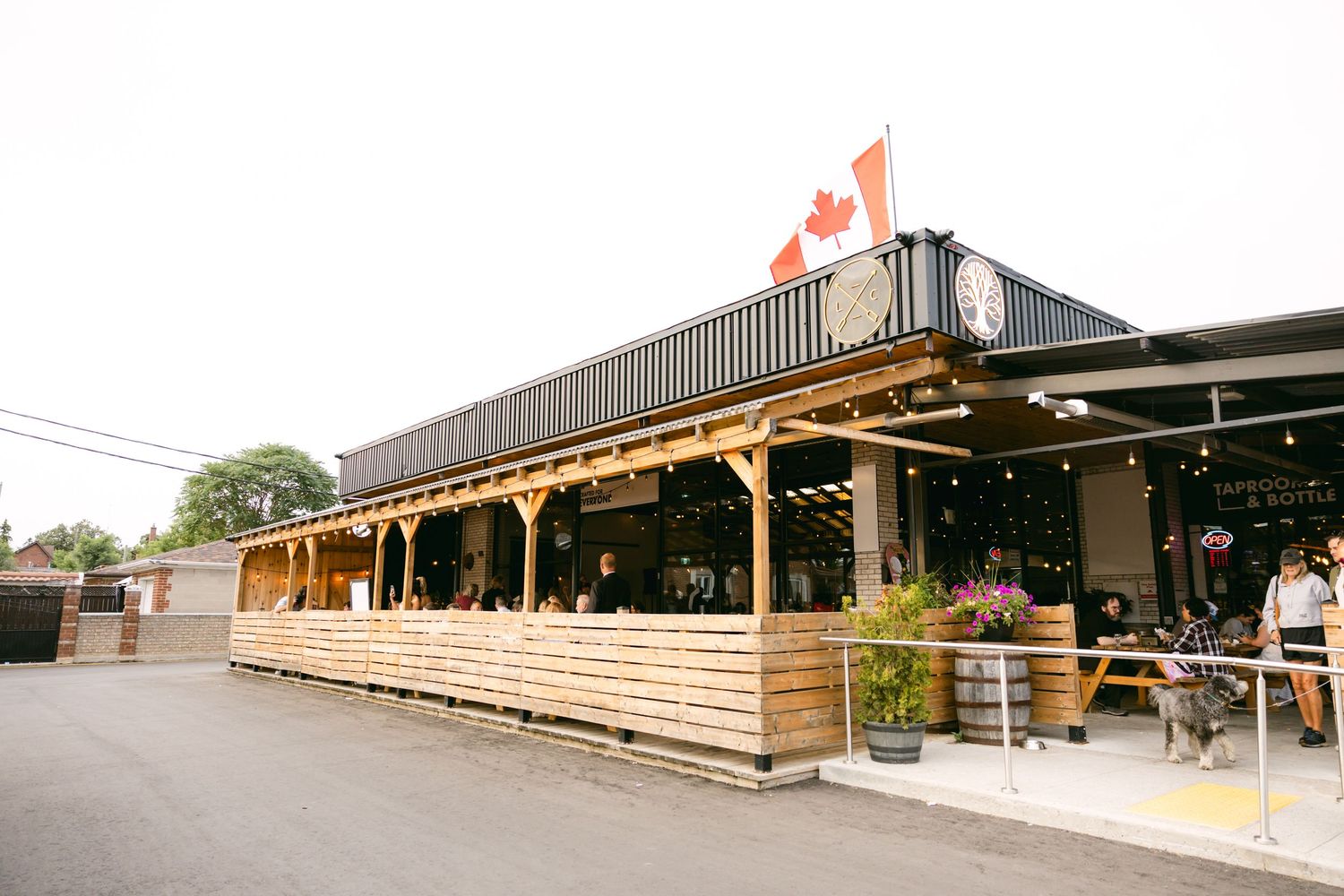 Rustic outdoor venue with wooden beams and Canadian flags flying overhead.