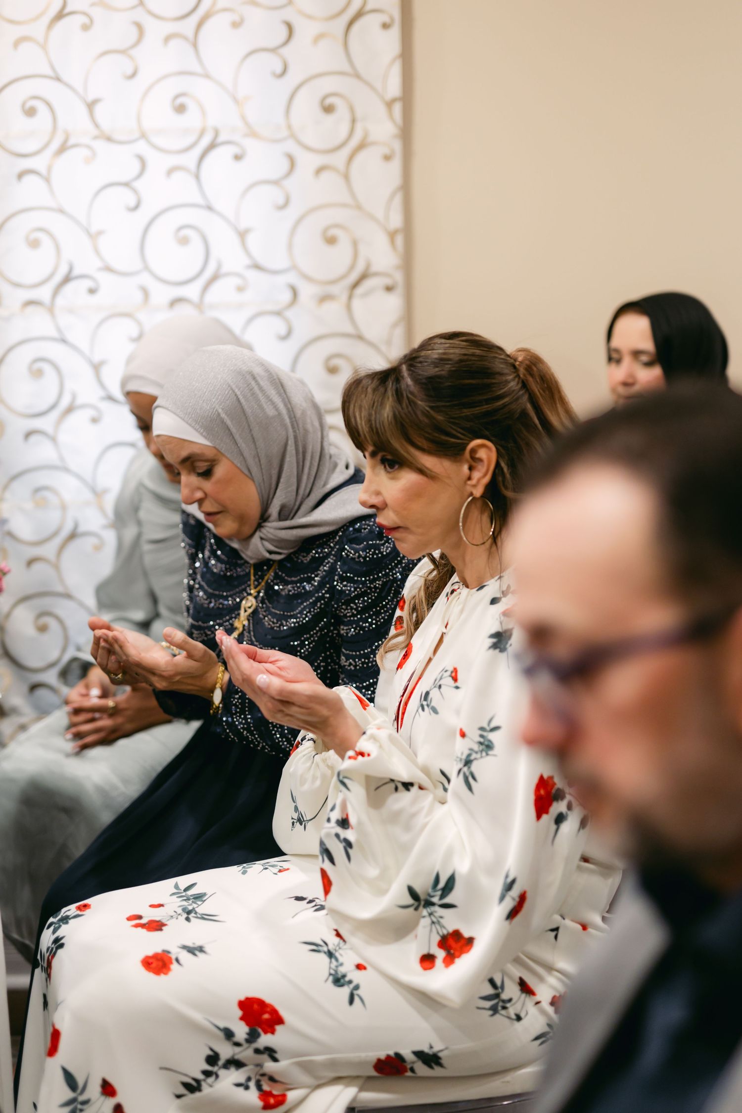 Guests in formal attire check their phones during a wedding ceremony.