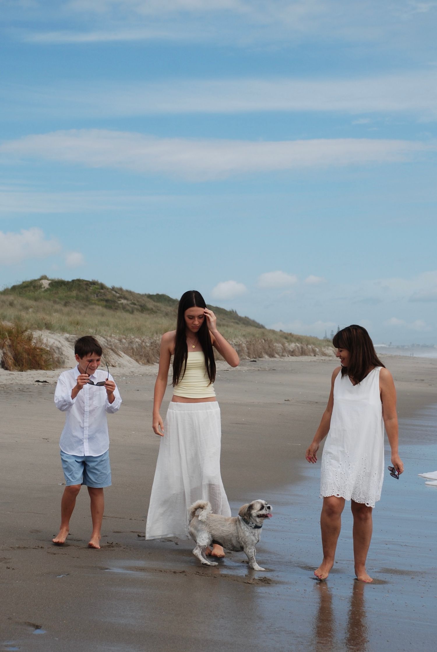 Mum walking with her two children and their dog along the sandy beach