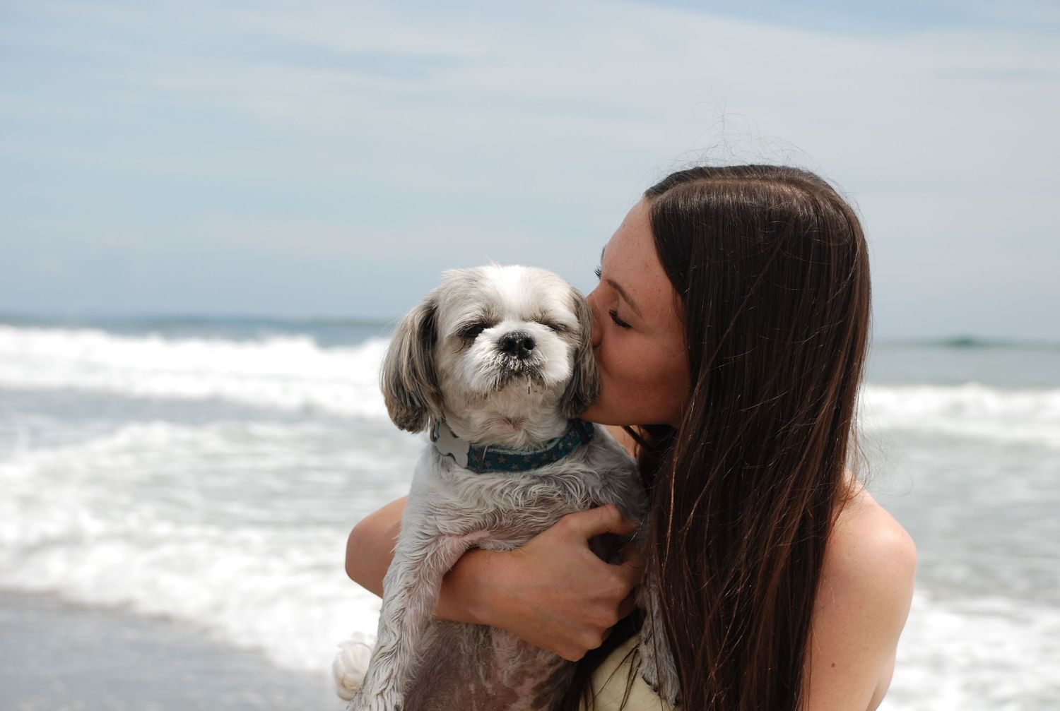 Young girl showing affection by hugging and kissing her dog’s cheek