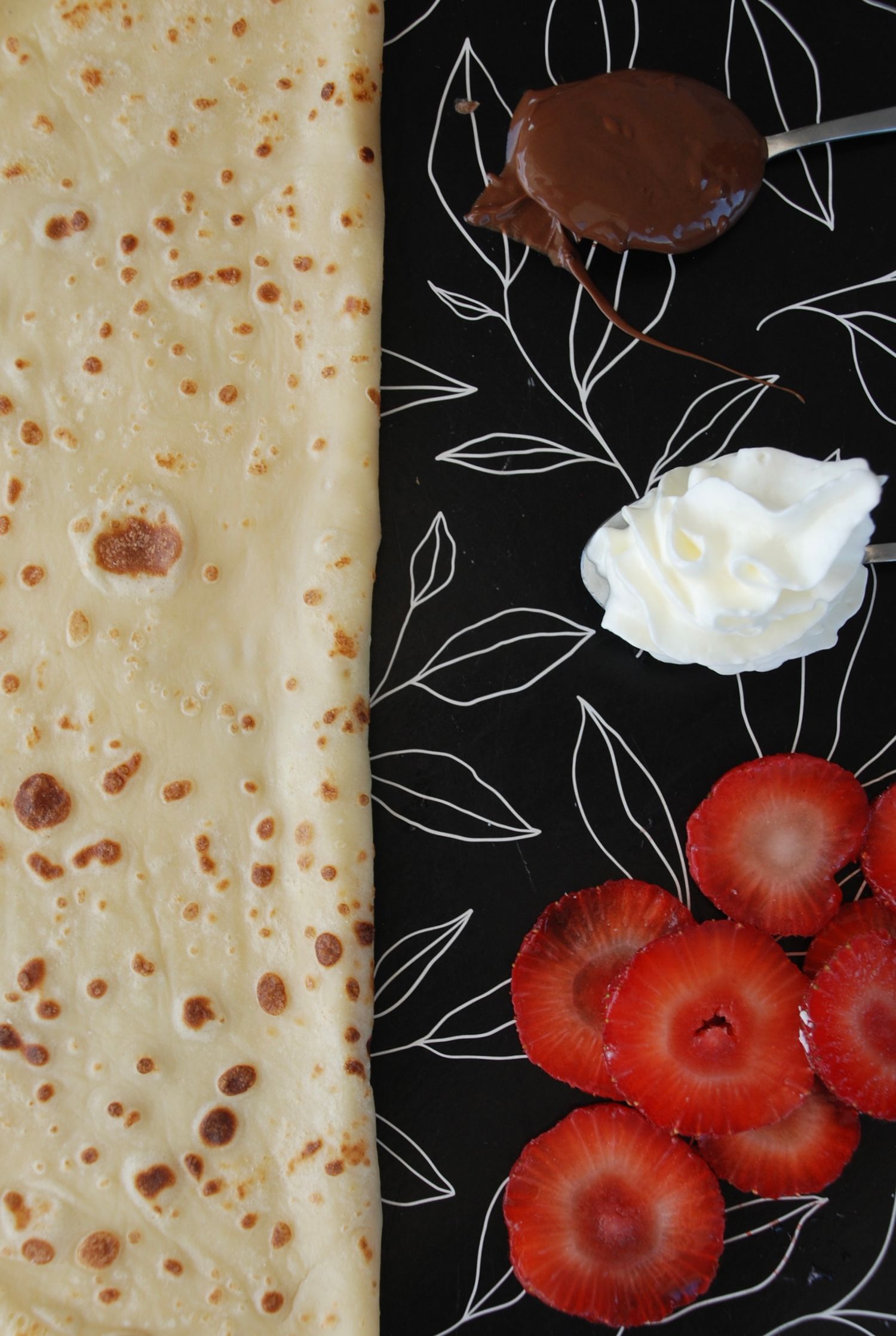 Golden crepe drizzled with chocolate sauce and fresh strawberries, topped with whipped cream.