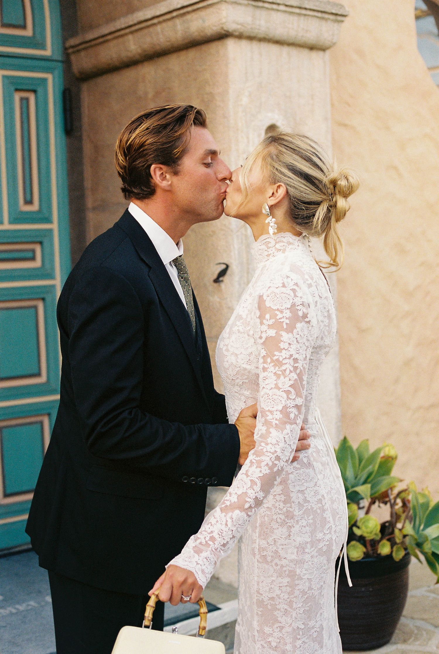 Romantic wedding couple sharing intimate moments against a turquoise and beige backdrop.